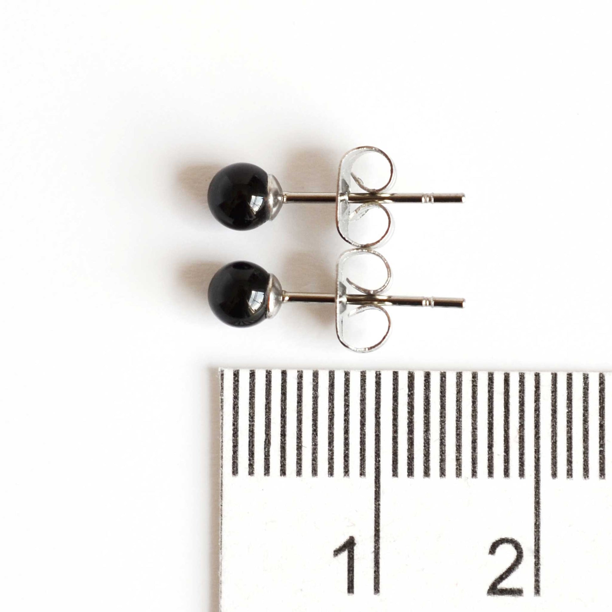 4mm Onyx stud earrings next to ruler