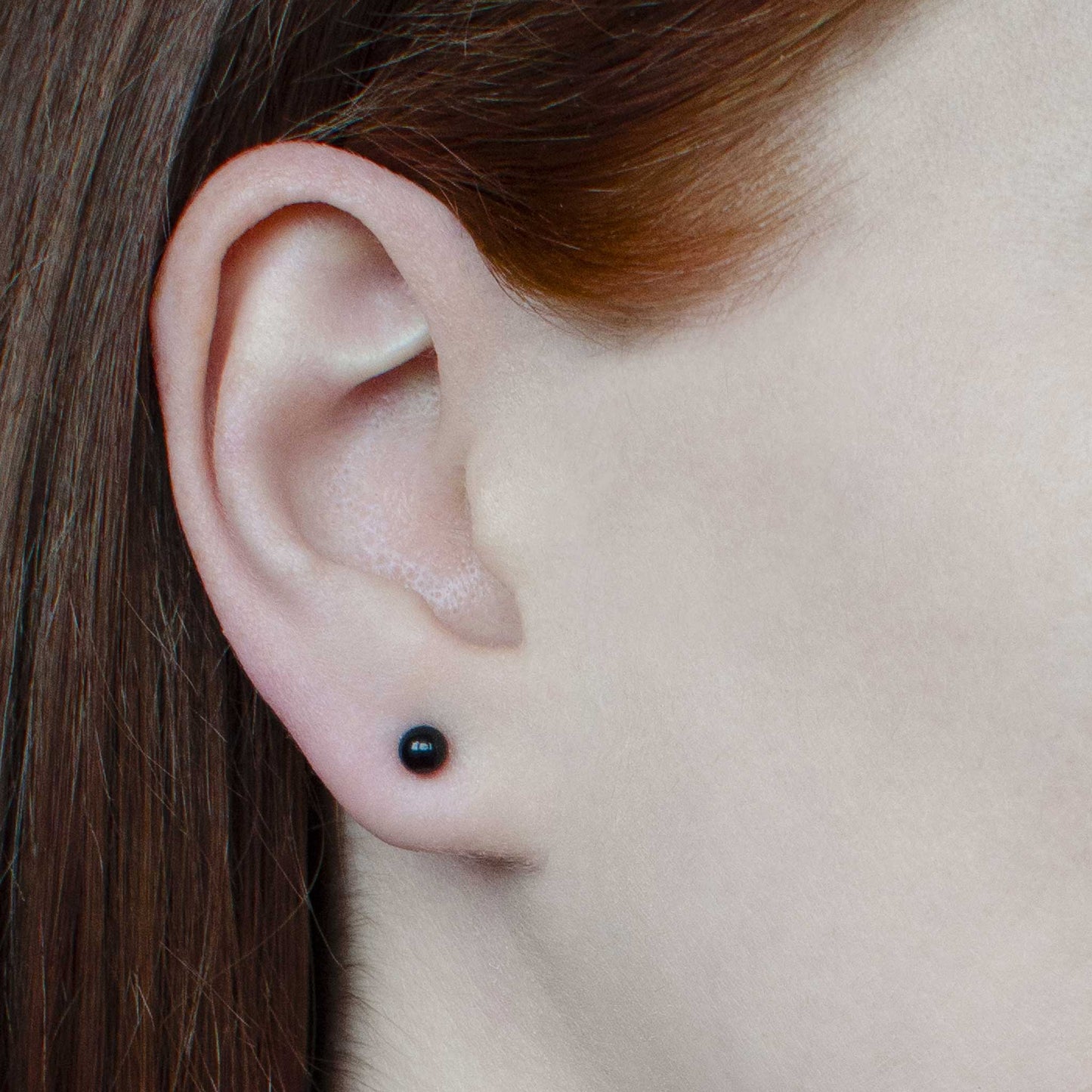 Woman wearing small black Onyx stud earring in earlobe