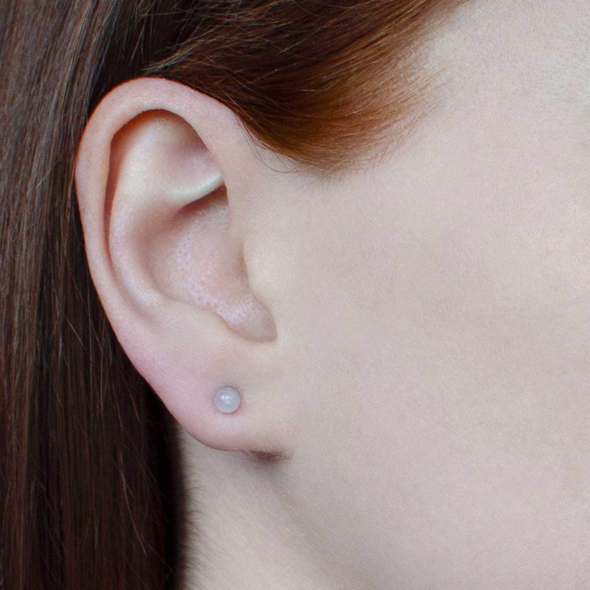 Woman wearing small Rose Quartz stud earring in earlobe