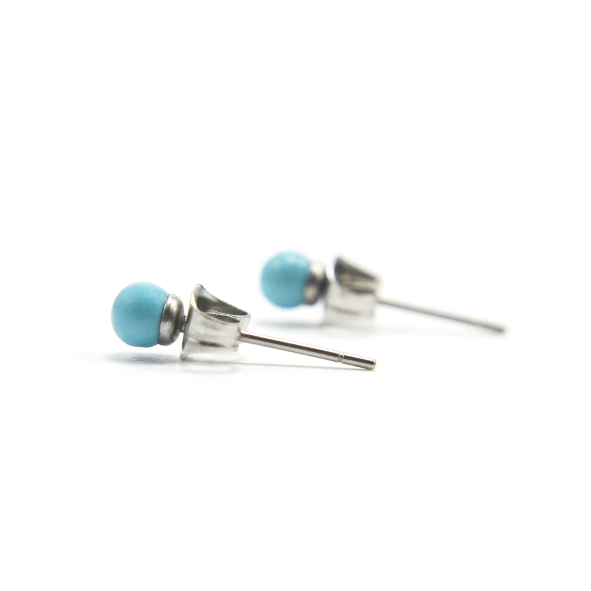 Small turquoise stud earrings side view on white background