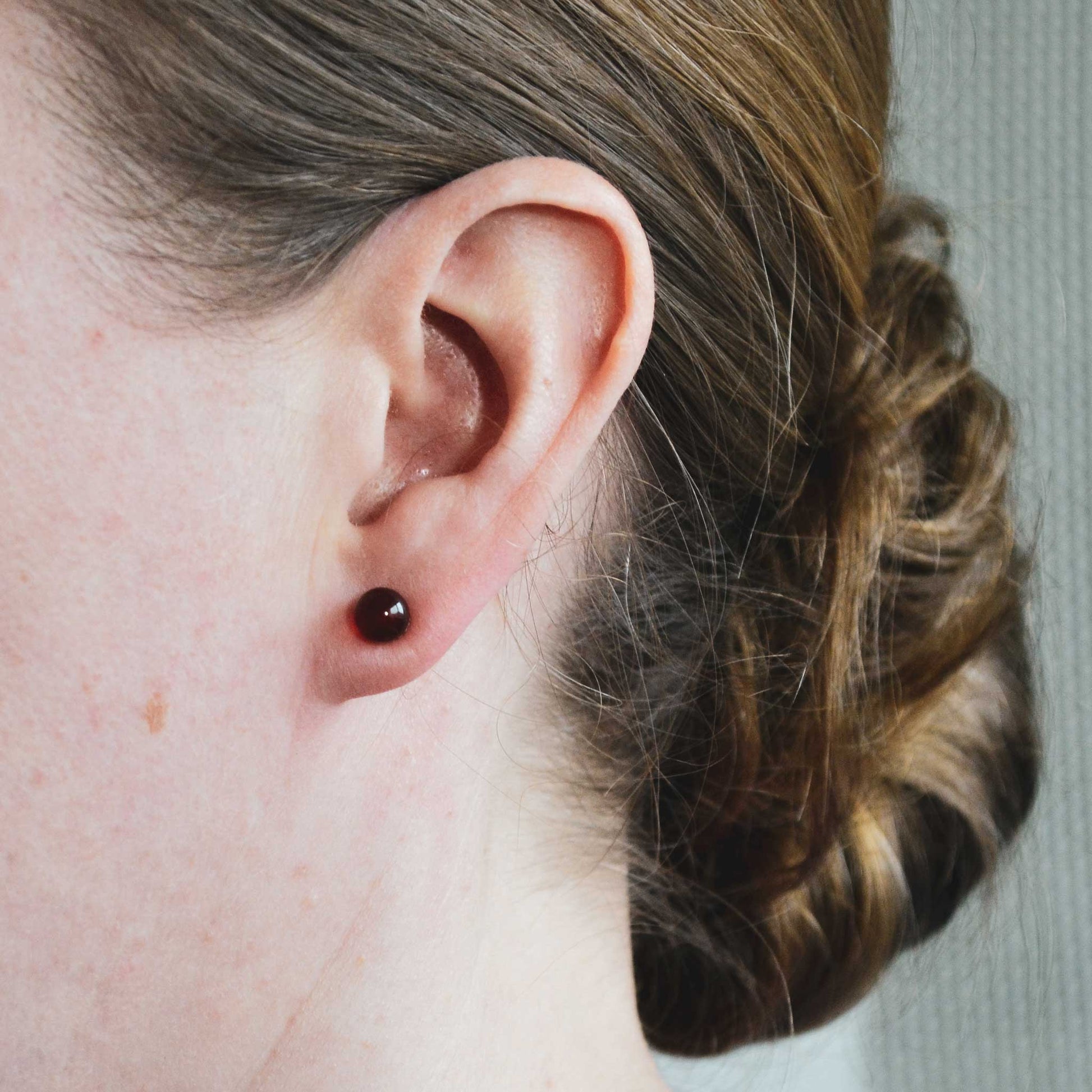 Woman wearing Carnelian stud earring in earlobe
