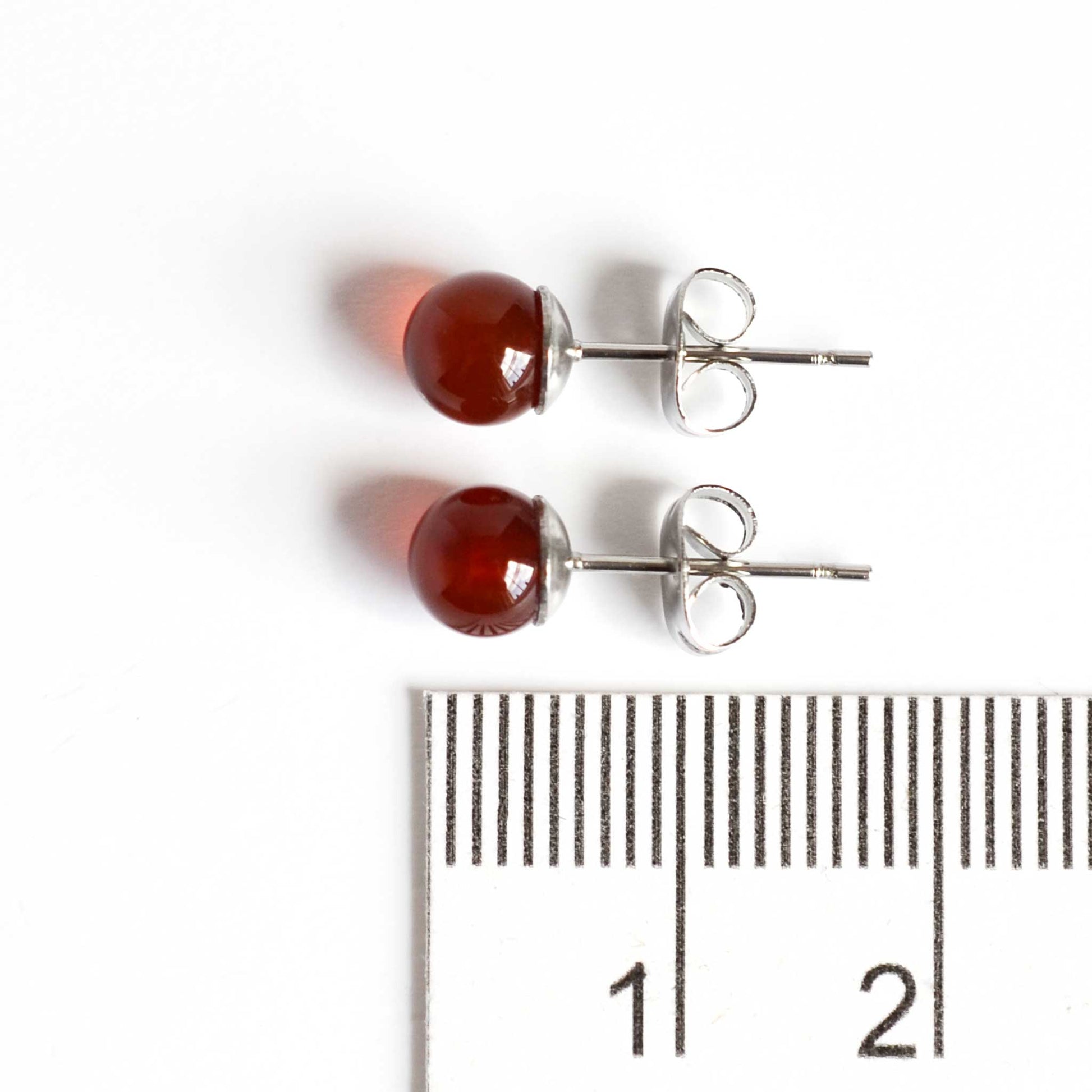 6mm Carnelian ball stud earrings next to ruler