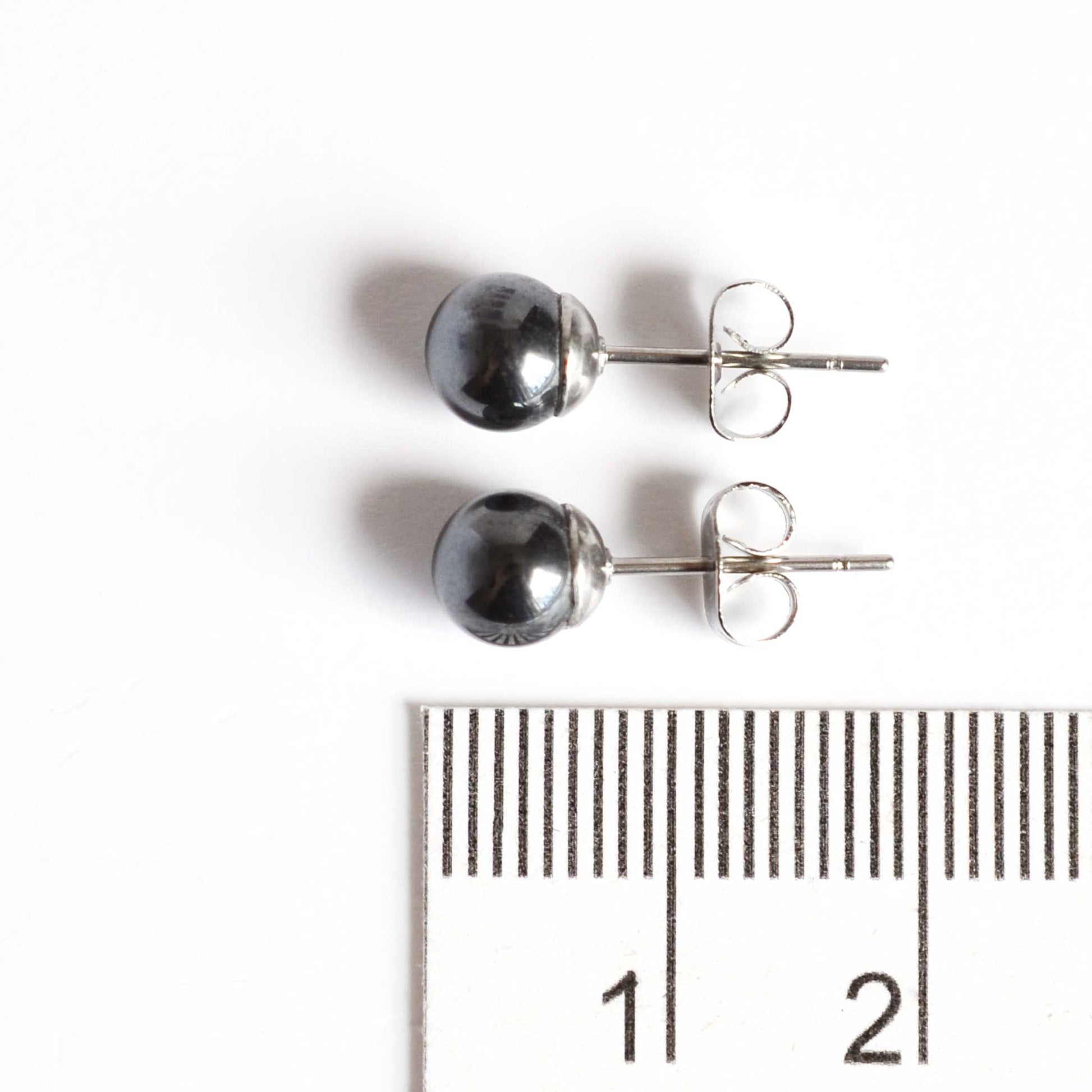 6mm Hematite ball earrings next to ruler