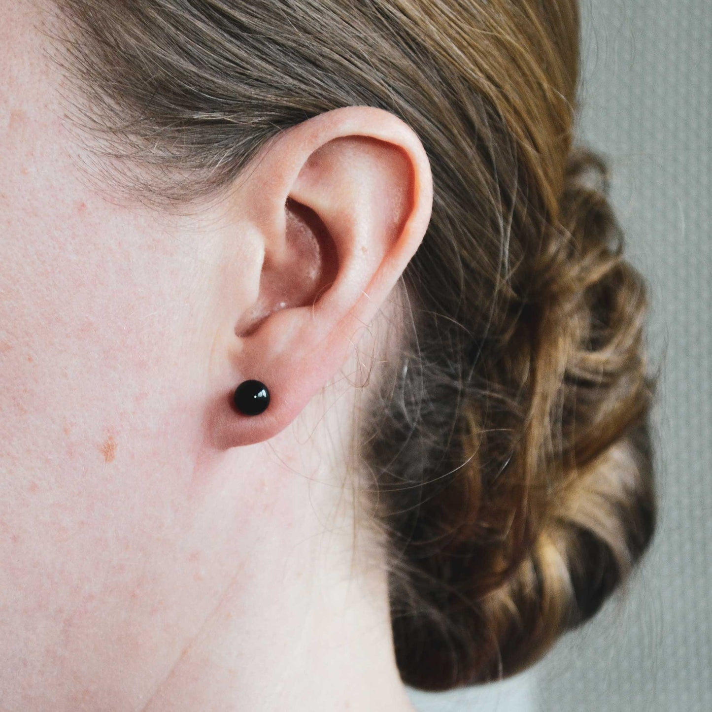 Woman wearing black Onyx ball stud earring in earlobe