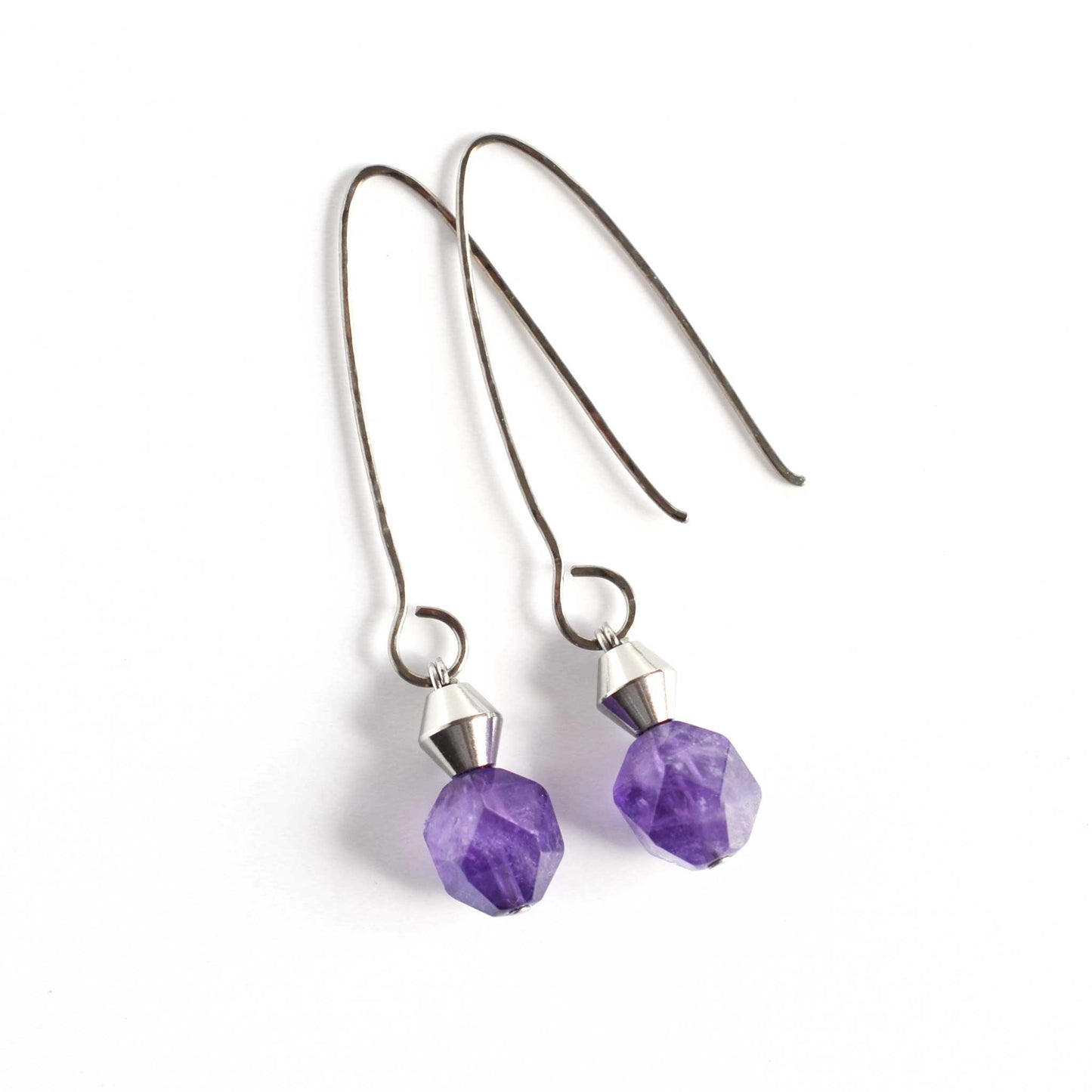Long Amethyst & Titanium drop earrings laying on white background.