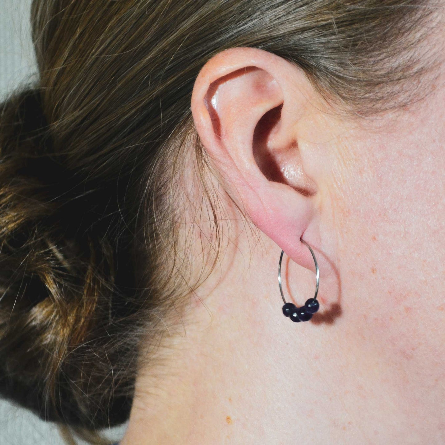 Woman wearing purple Amethyst hoop earring in earlobe