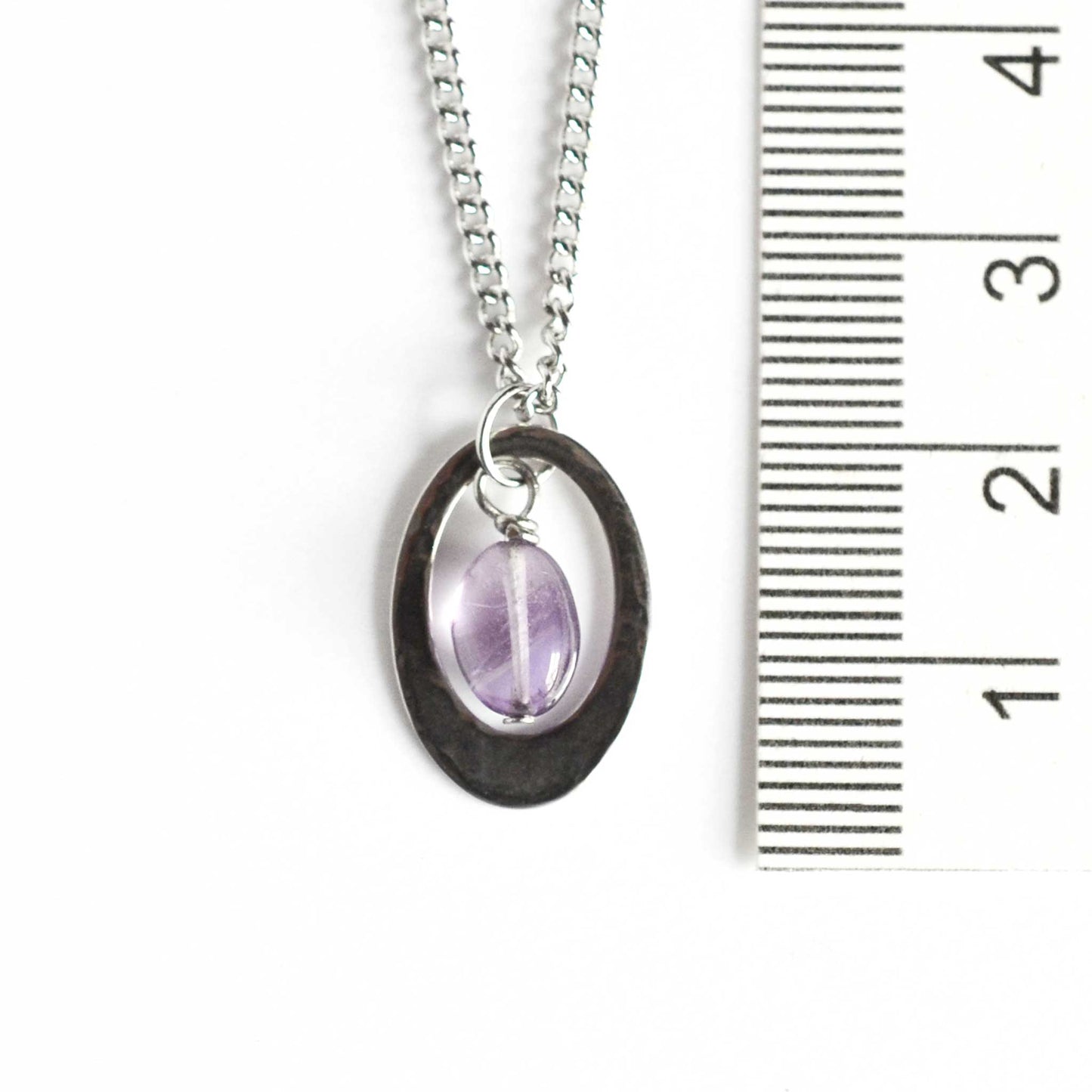 Dainty oval Amethyst pendant necklace next to ruler.