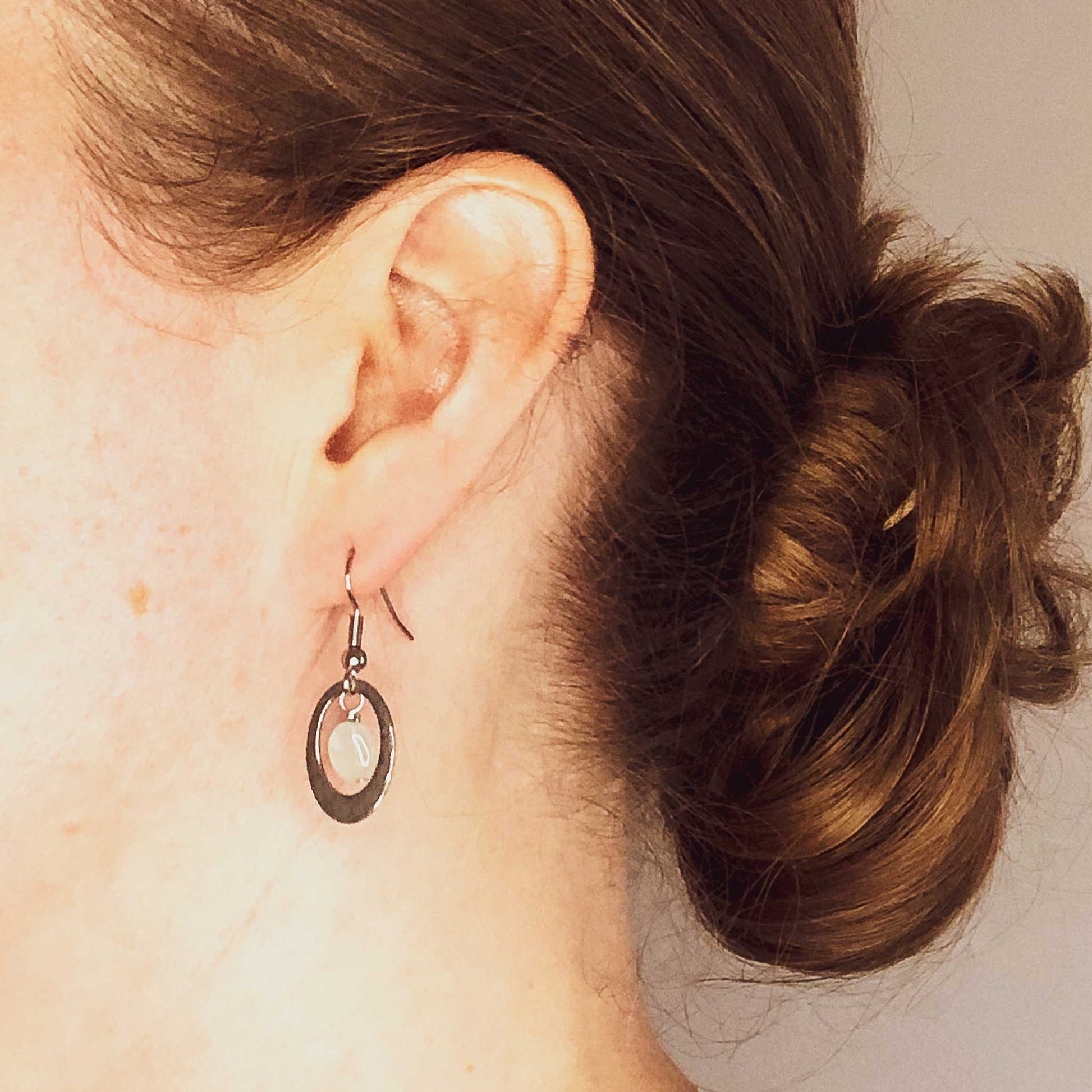 Woman wearing hypoallergenic Aquamarine oval drop earrings.