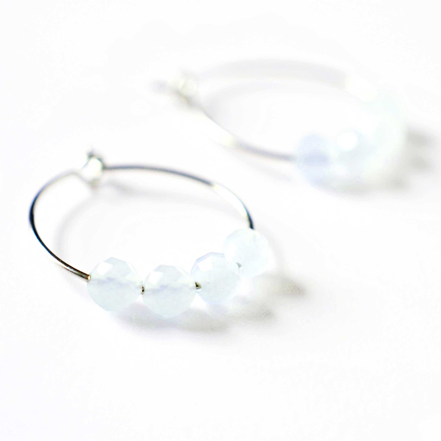Close up of Aquamarine hoop earrings with four small round faceted pale blue Aquamarine beads