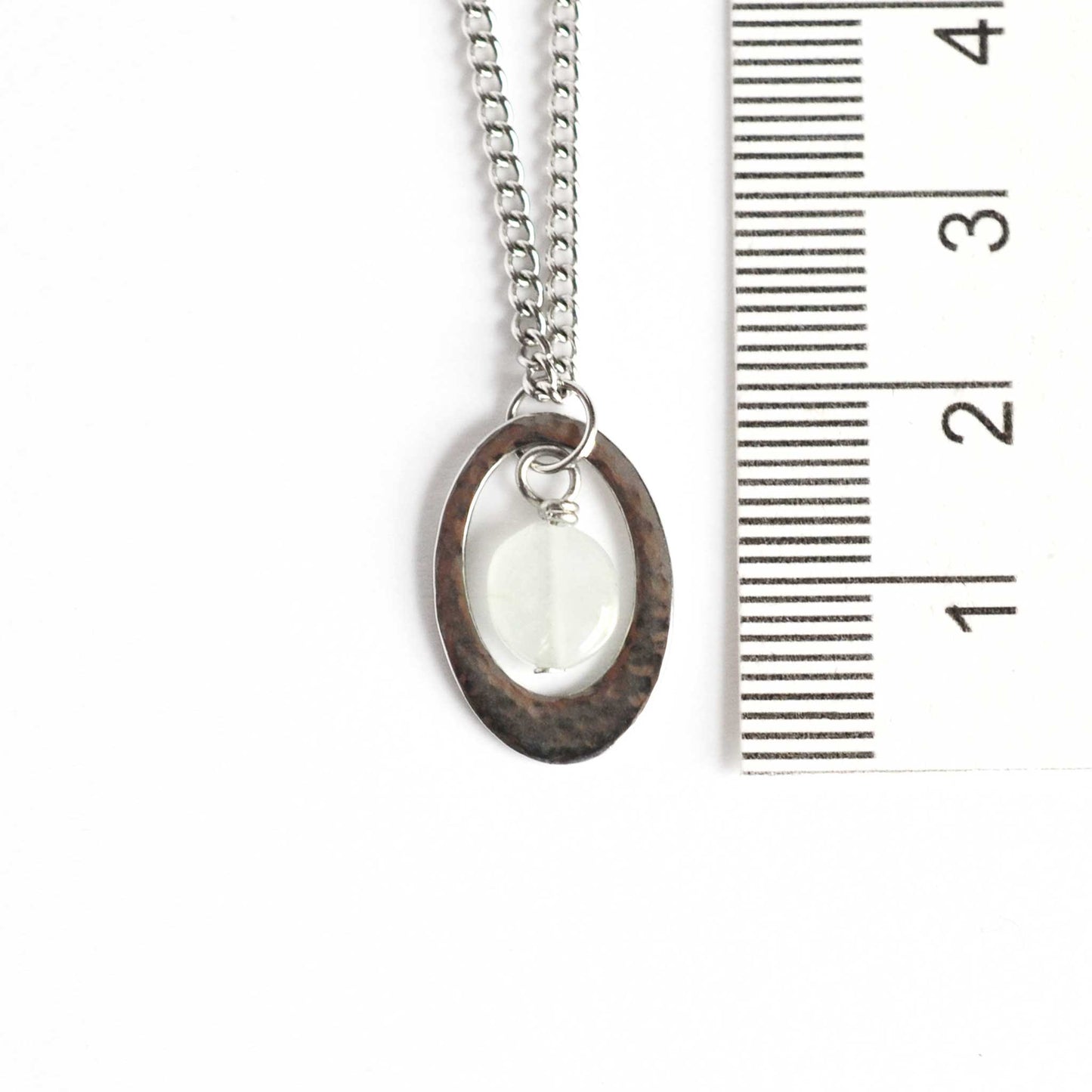 Dainty oval Aquamarine pendant necklace next to ruler.