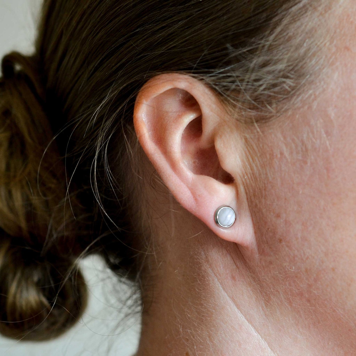 Woman wearing pale Blue Lace Agate stud earring in earlobe