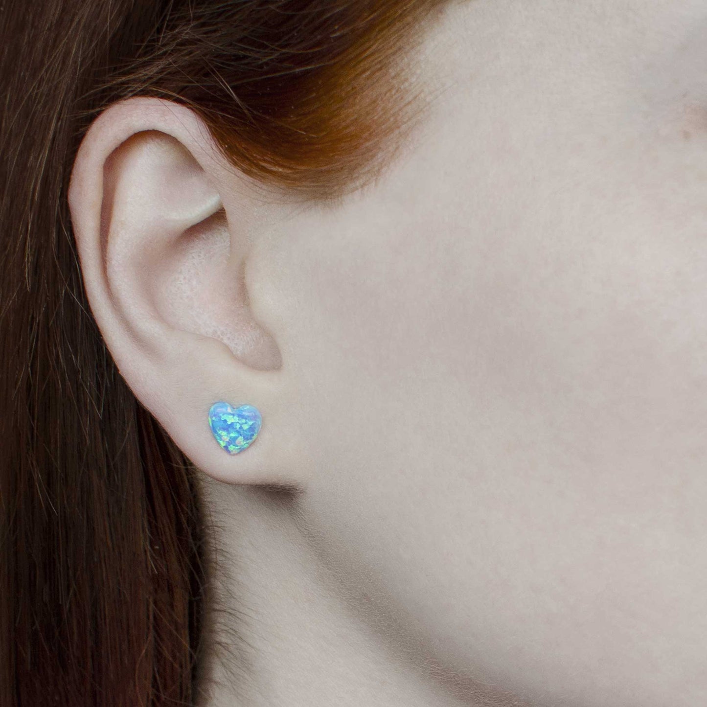 Woman wearing light blue Opal heart earring in earlobe