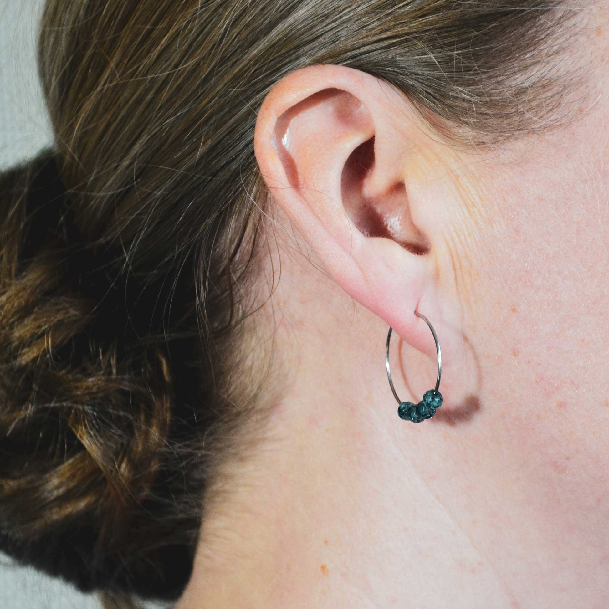 Woman wearing blue Topaz hoop earring in earlobe