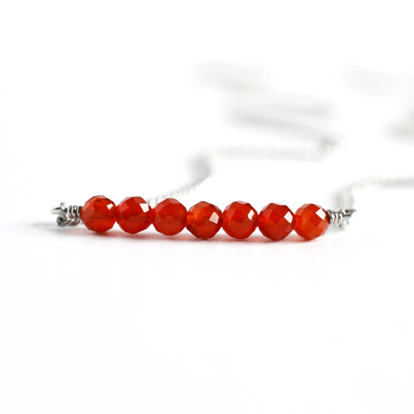 Close up of Carnelian necklace with seven small round faceted orange Carnelian gemstones