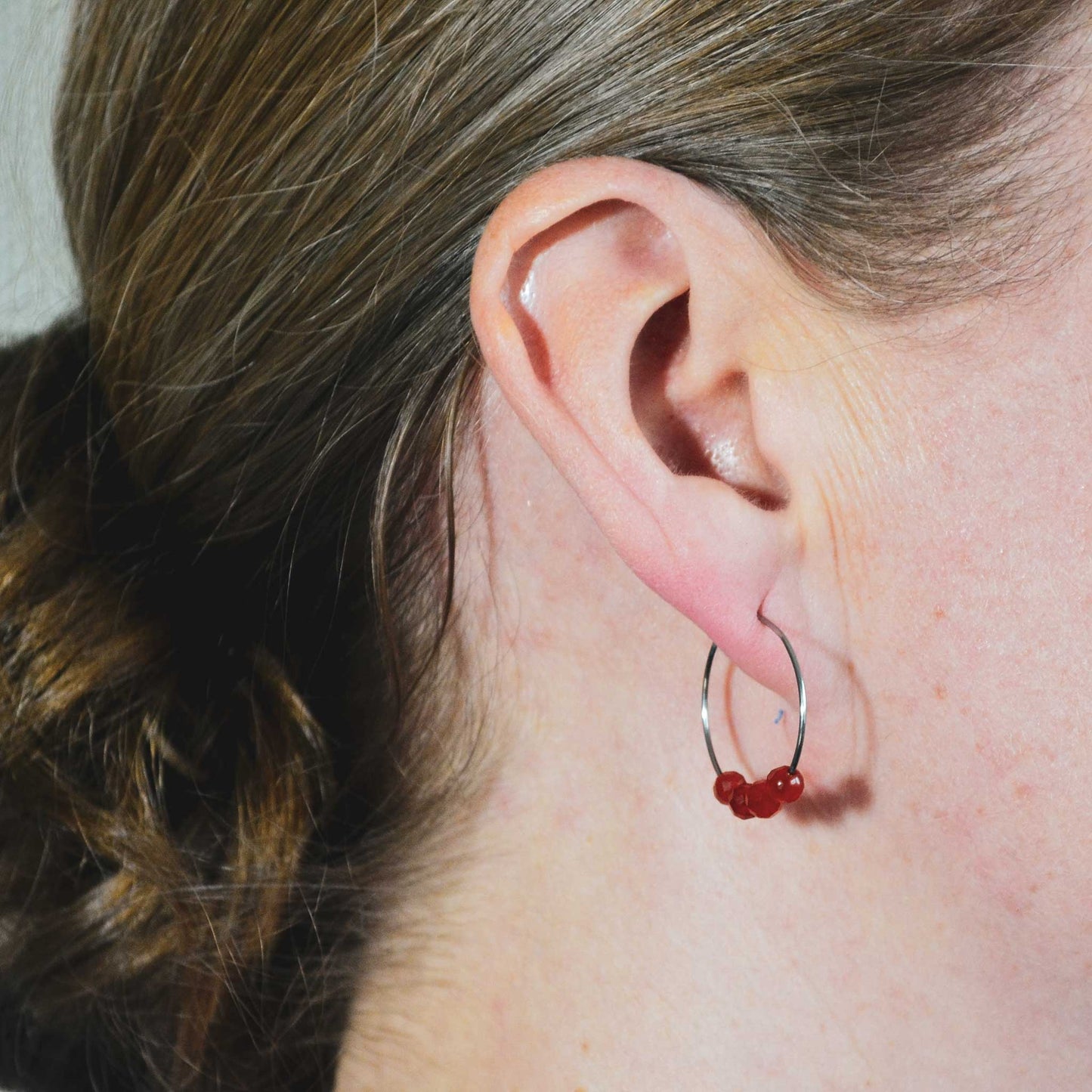 Woman wearing orange Carnelian gemstone hoop earring in lobe