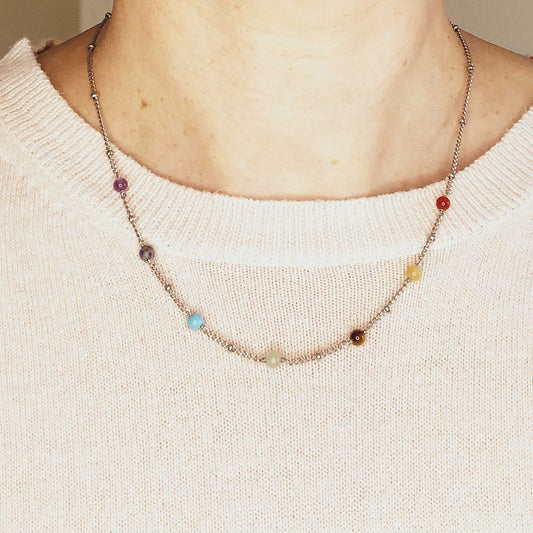 Woman wearing pink jumper and dainty gemstone chakra necklace