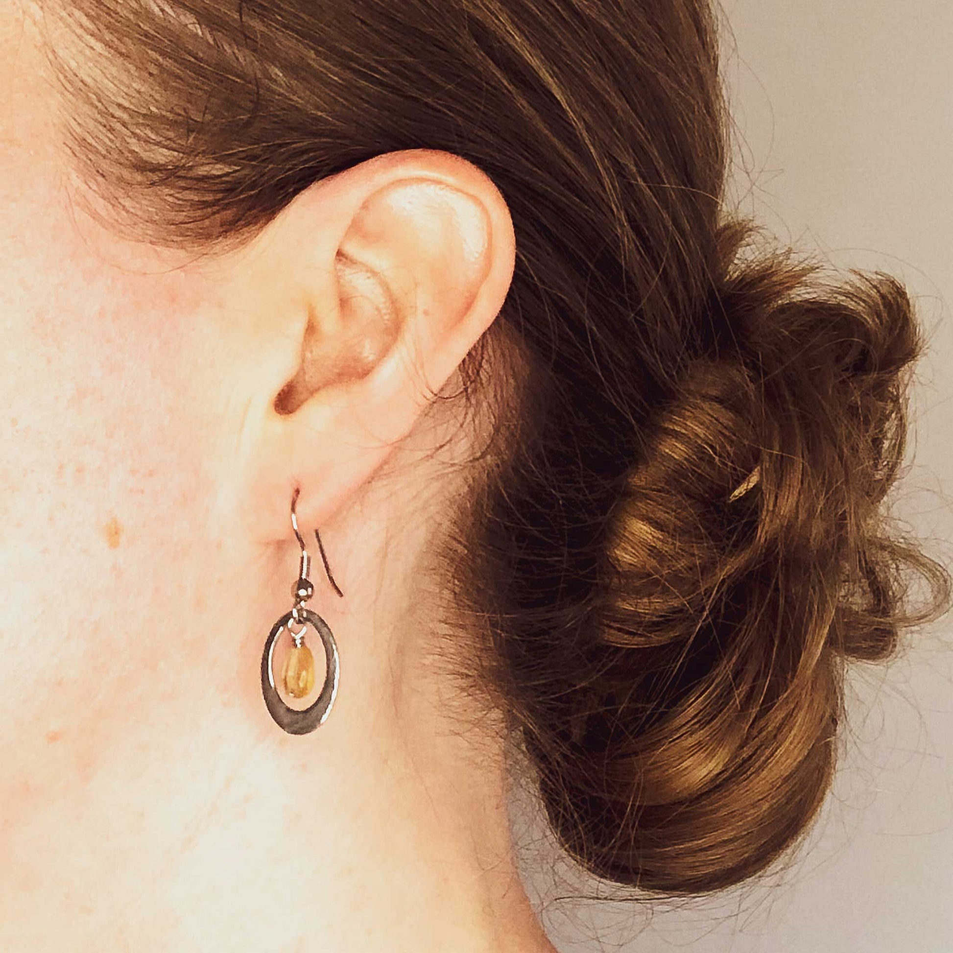 Woman wearing hypoallergenic Citrine oval drop earrings.