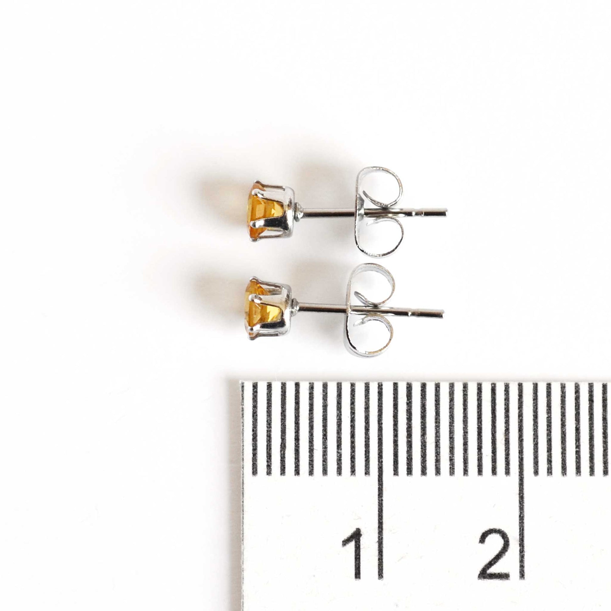 4mm Citrine stud earrings next to ruler