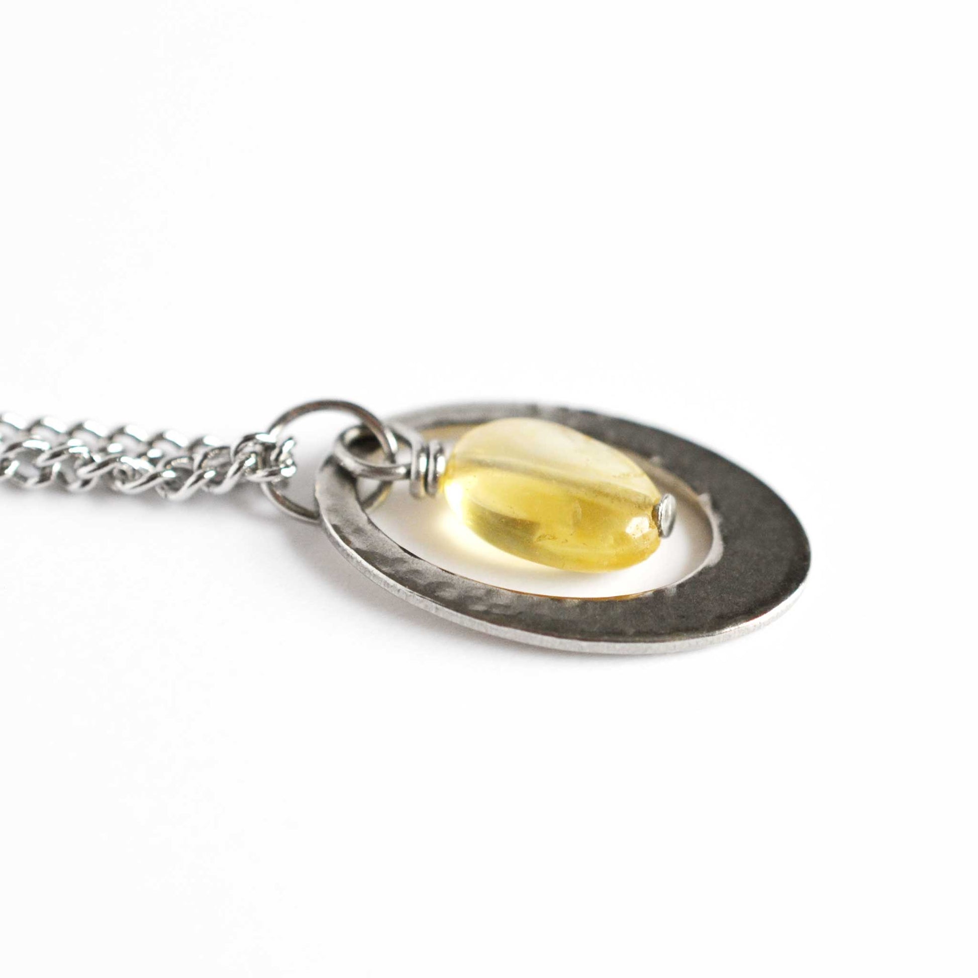 Close up of yellow Citrine gemstone and stainless steel oval pendant necklace.
