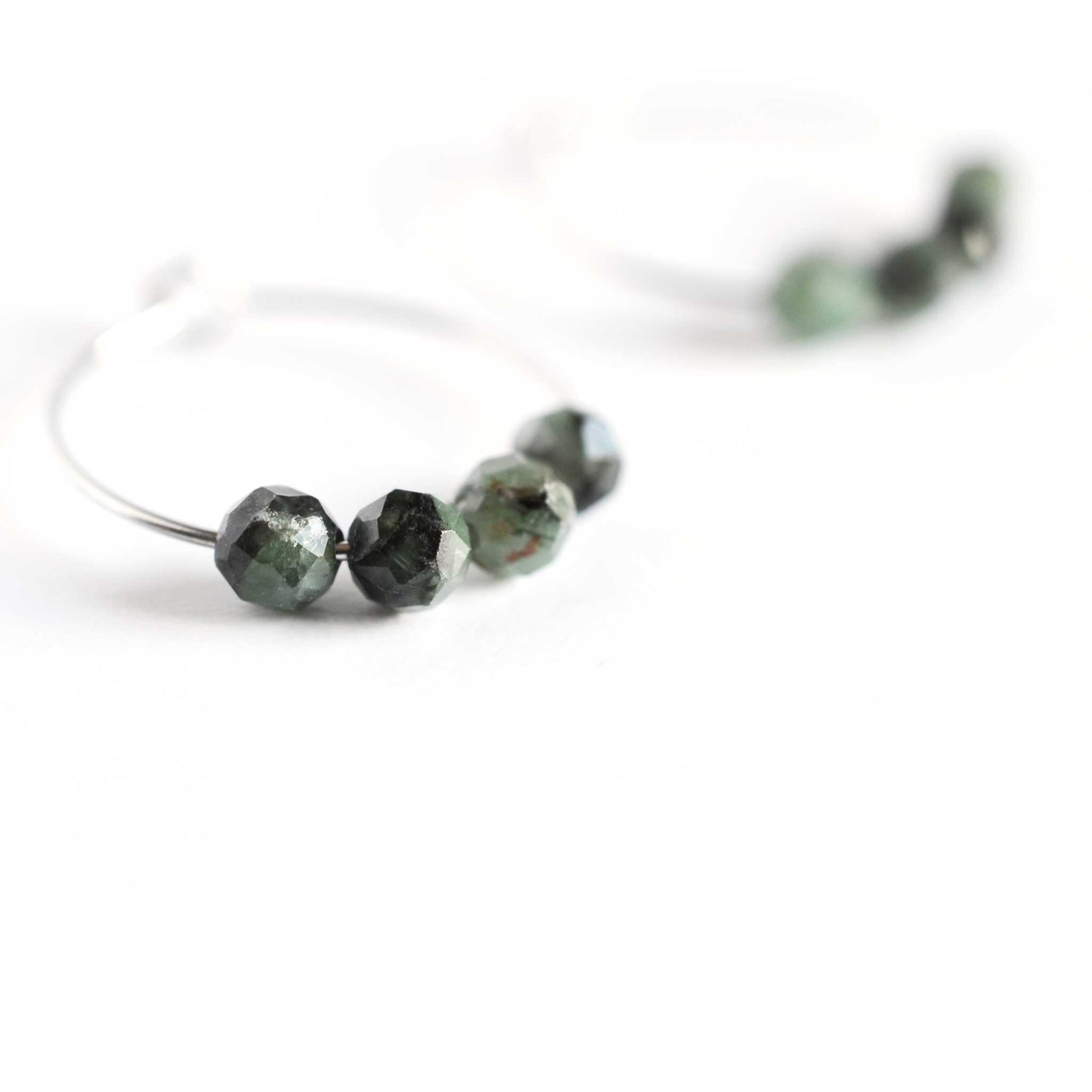 Close up of Emerald hoop earrings with four small round faceted dark green natural Emerald beads