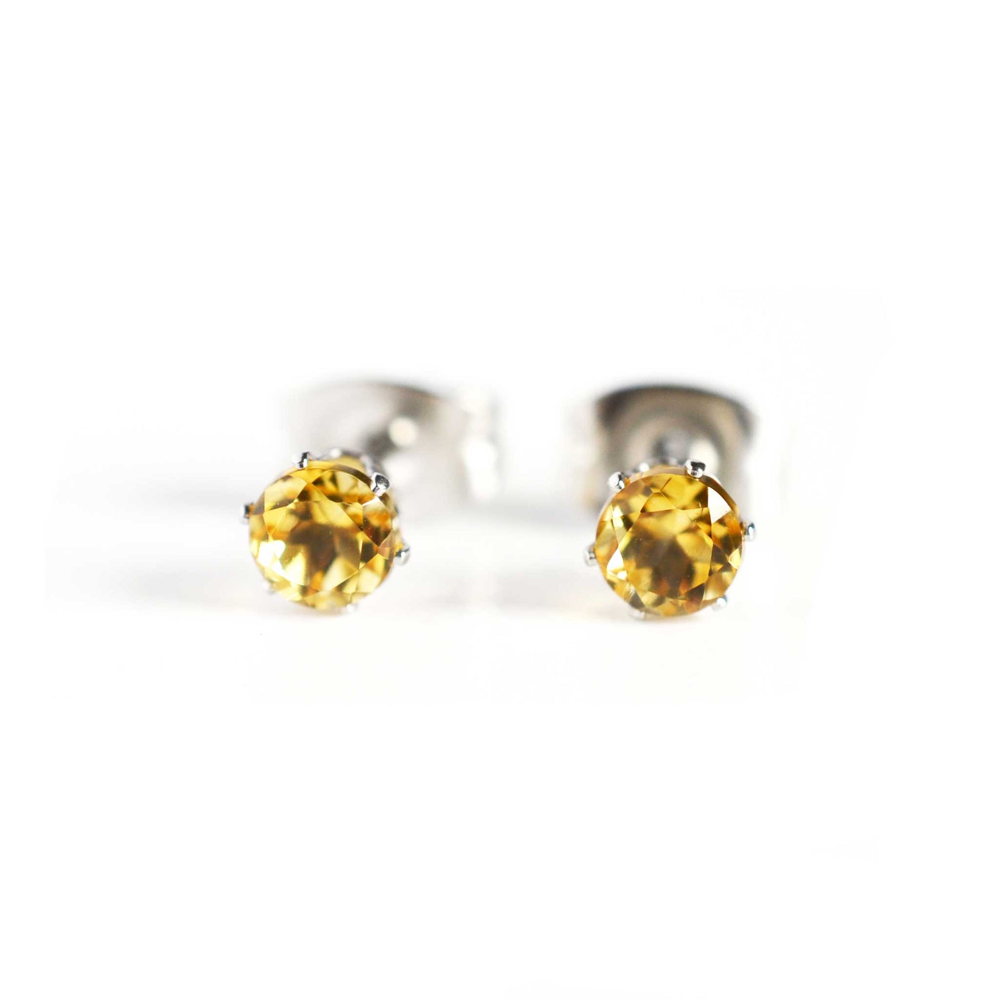 Front view of small yellow faceted Citrine stud earrings on white background