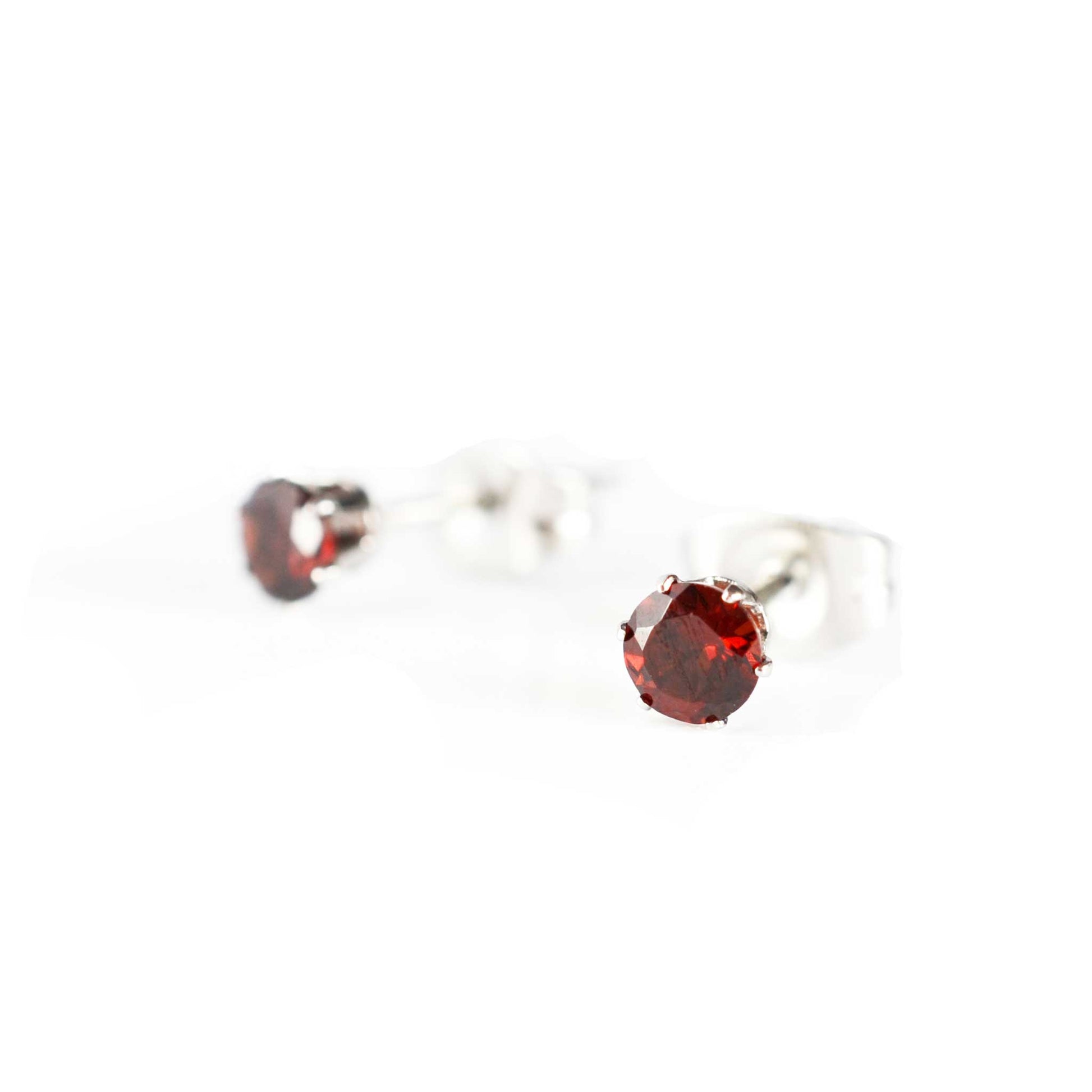 Tiny dark red Garnet stud earrings on white background
