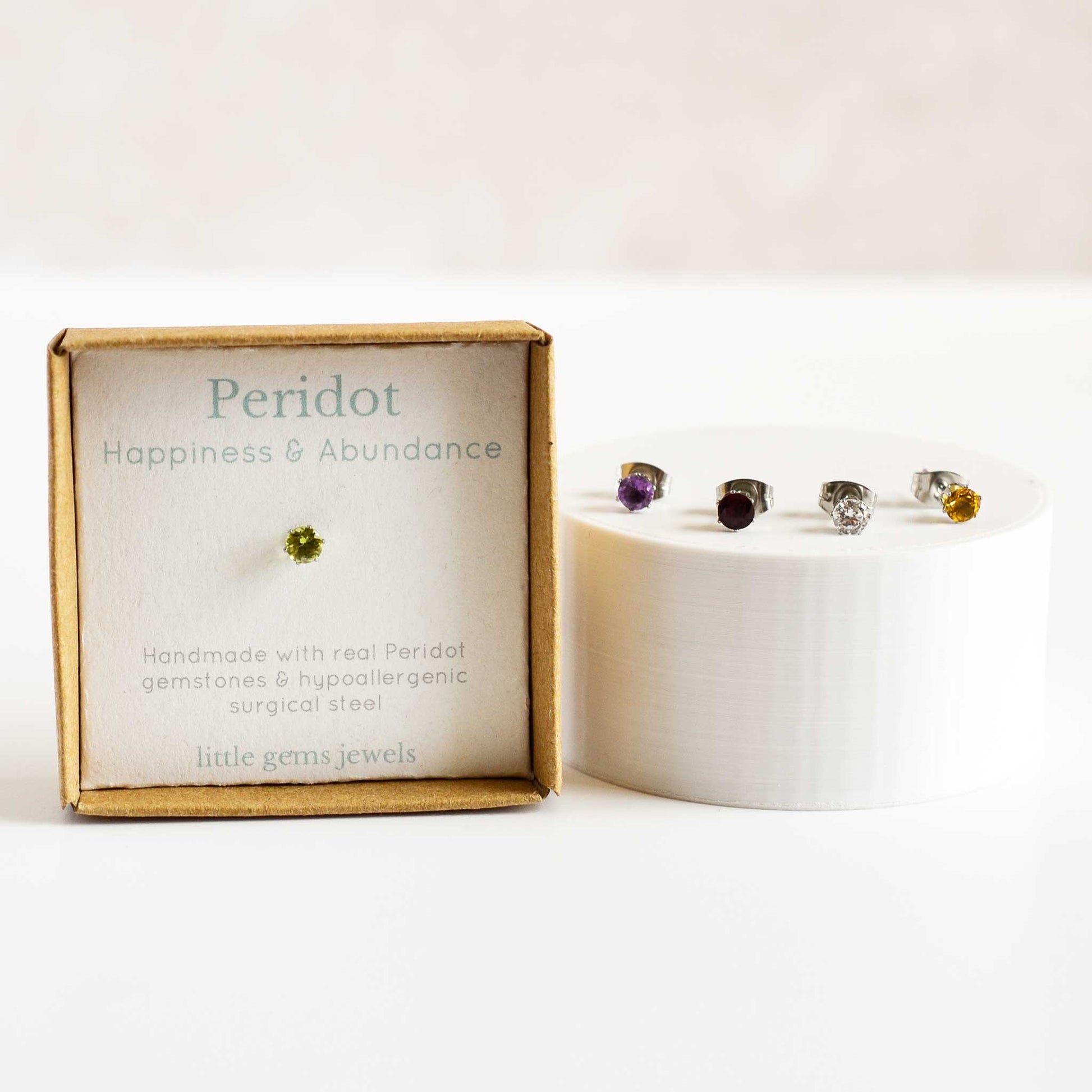 Single peridot gemstone earring in gift box with four different coloured stone studs by the side
