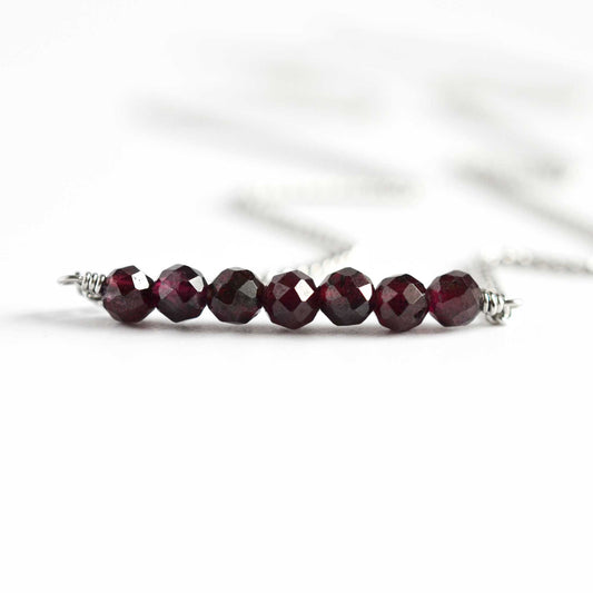 Close up of Garnet crystal necklace with seven small round faceted dark red Garnet gemstone beads
