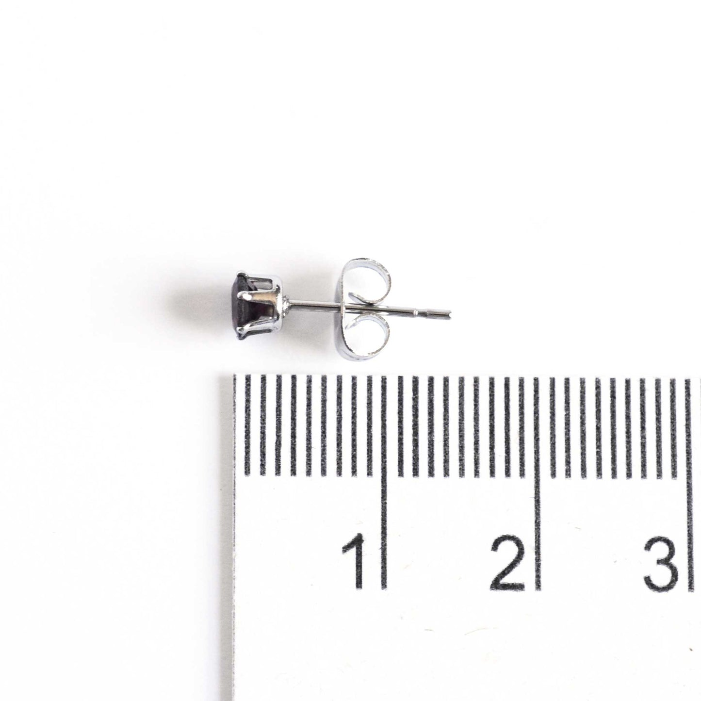 Small gemstone stud earring lying next to ruler measuring 15mm long