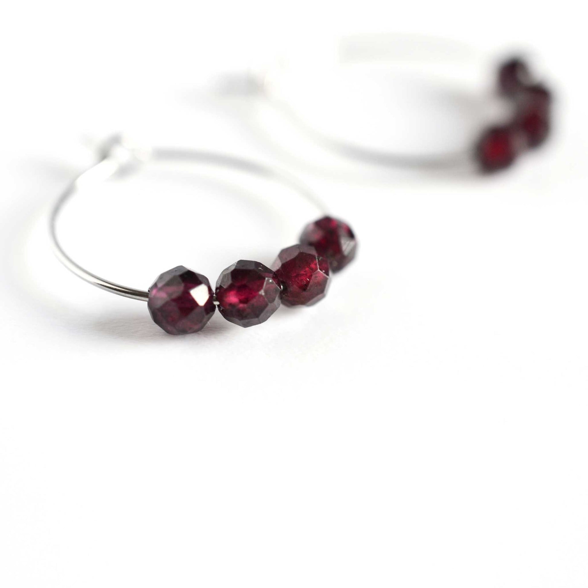 Close up of hoop earrings Garnet with four small round faceted dark red Garnet gemstone beads