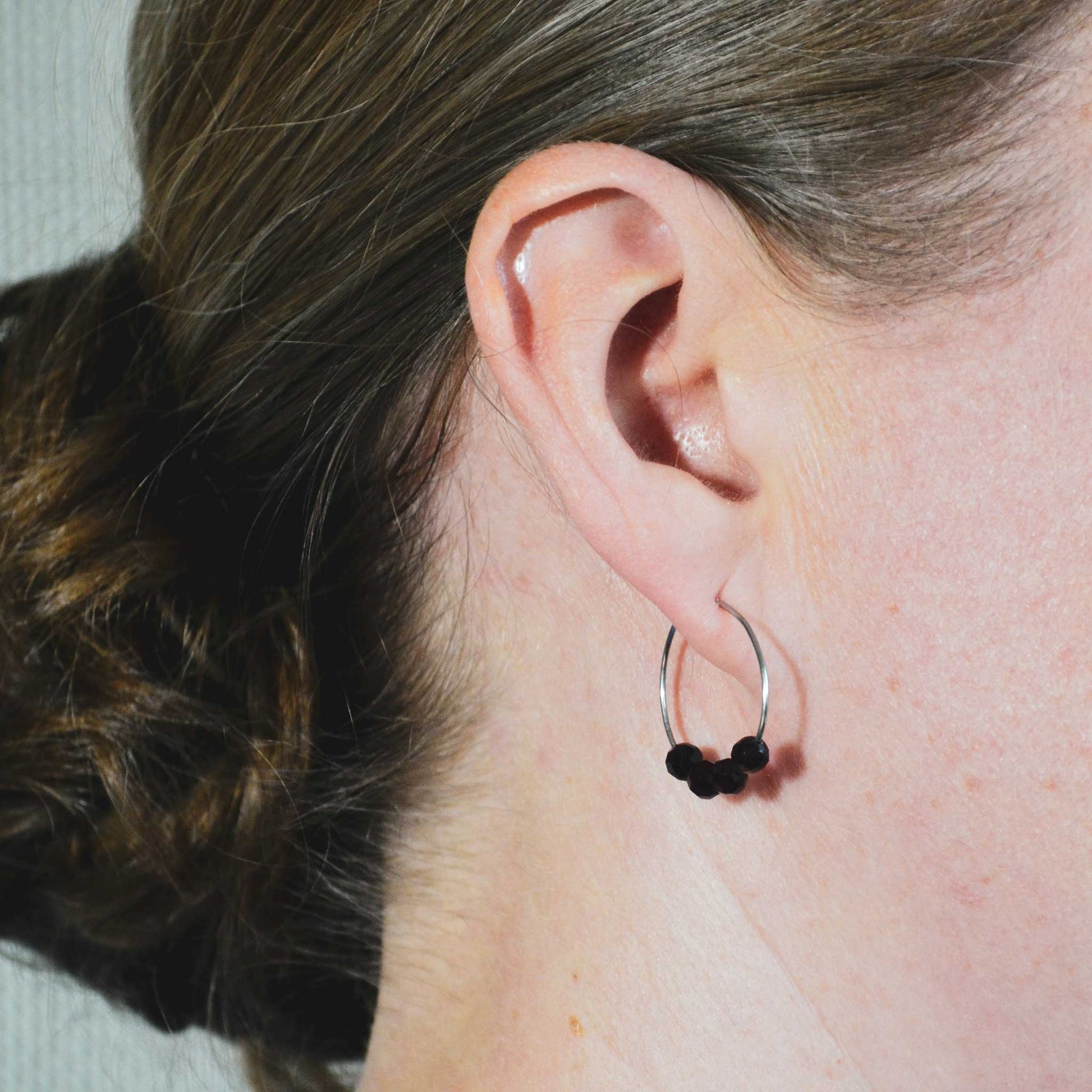 Woman wearing dark red Garnet hoop earrings in earlobe