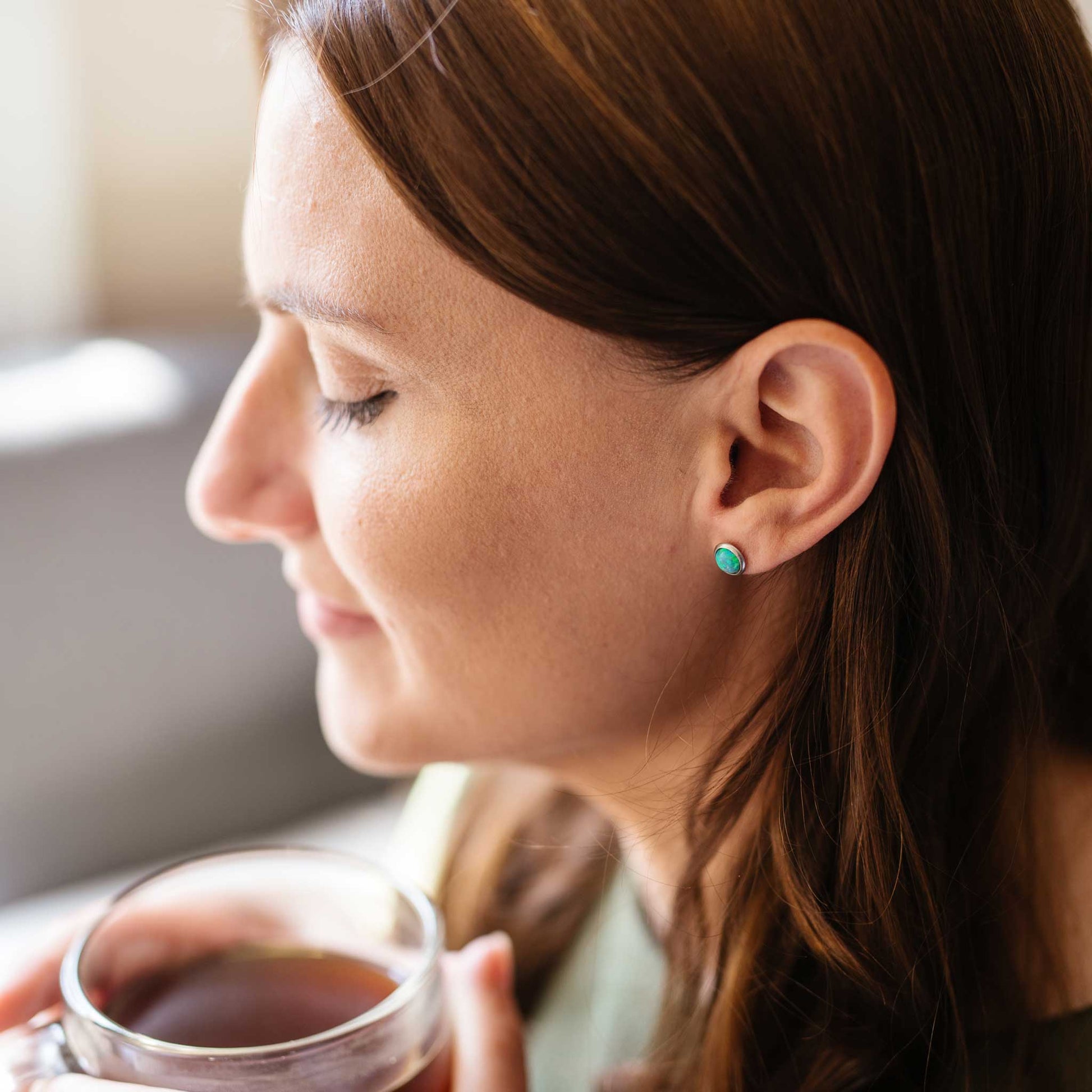Women wearing green Opal earrings whilst drinking tea