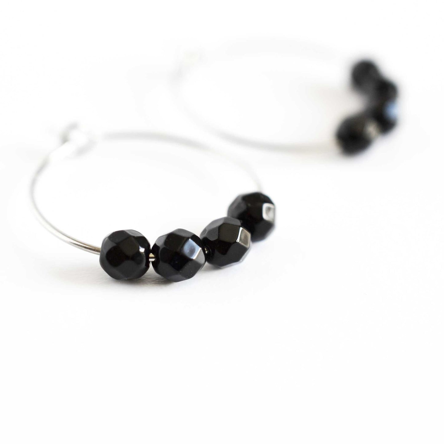 Close up of black hoop earrings with four small round faceted Onyx gemstone beads