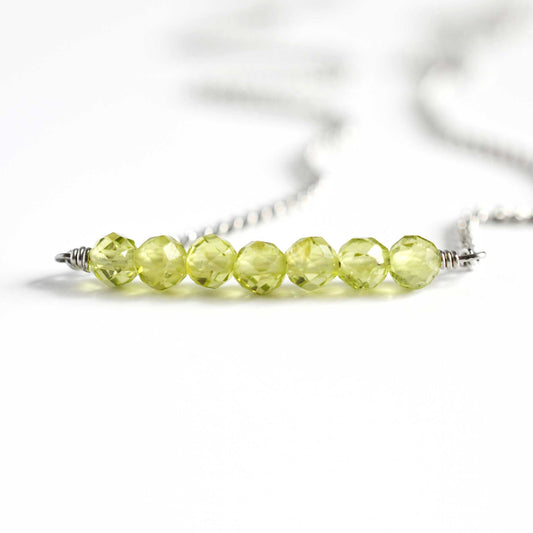 Close up of Peridot crystal necklace with seven small round faceted green Peridot gemstone beads