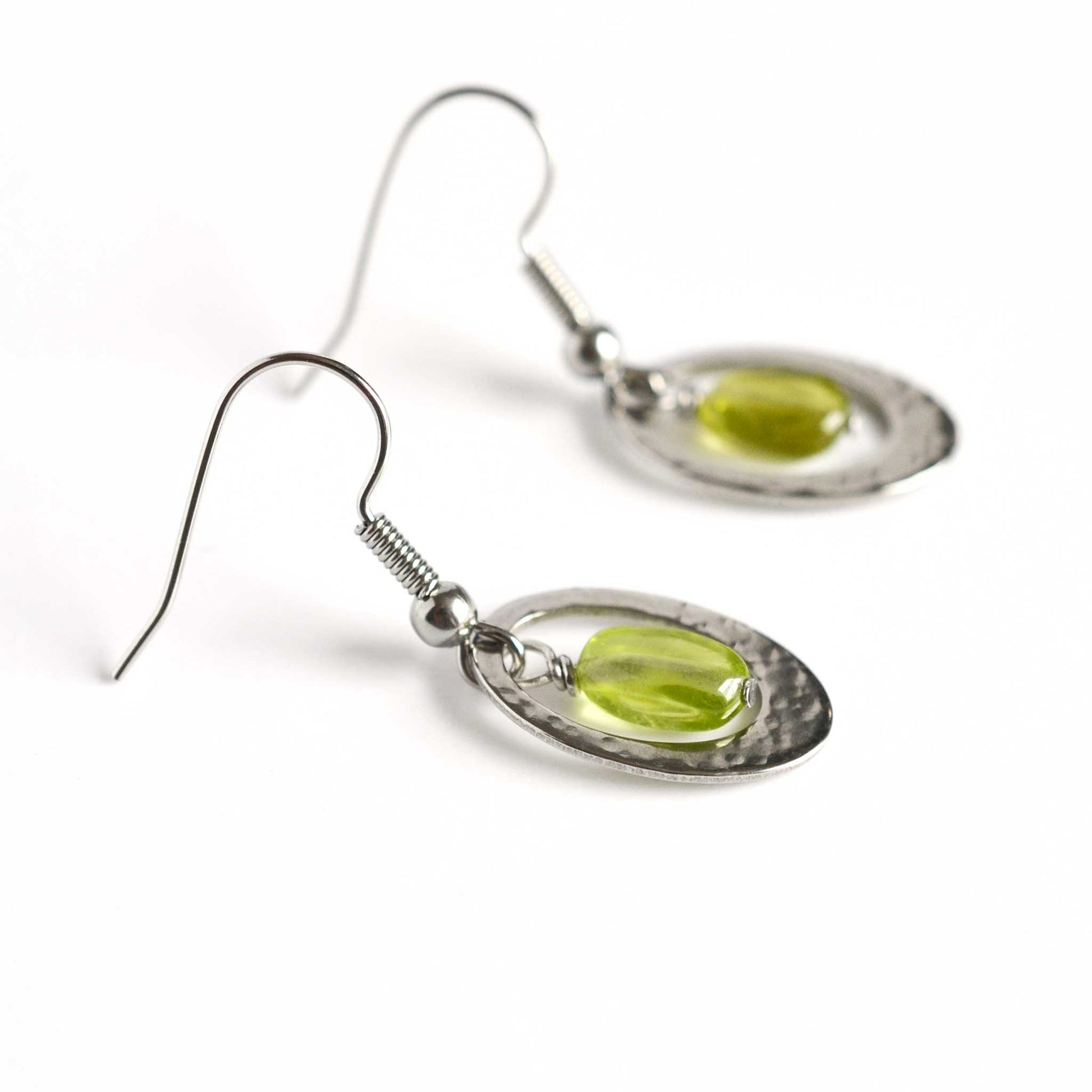 Side view detail of green Peridot gemstone and steel hammered oval drop earrings.