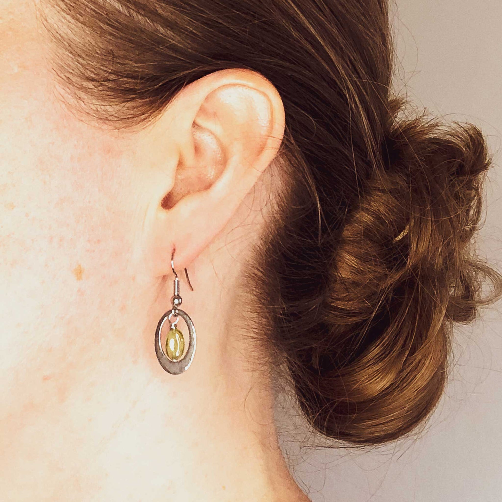 Woman wearing hypoallergenic green Peridot oval drop earrings.