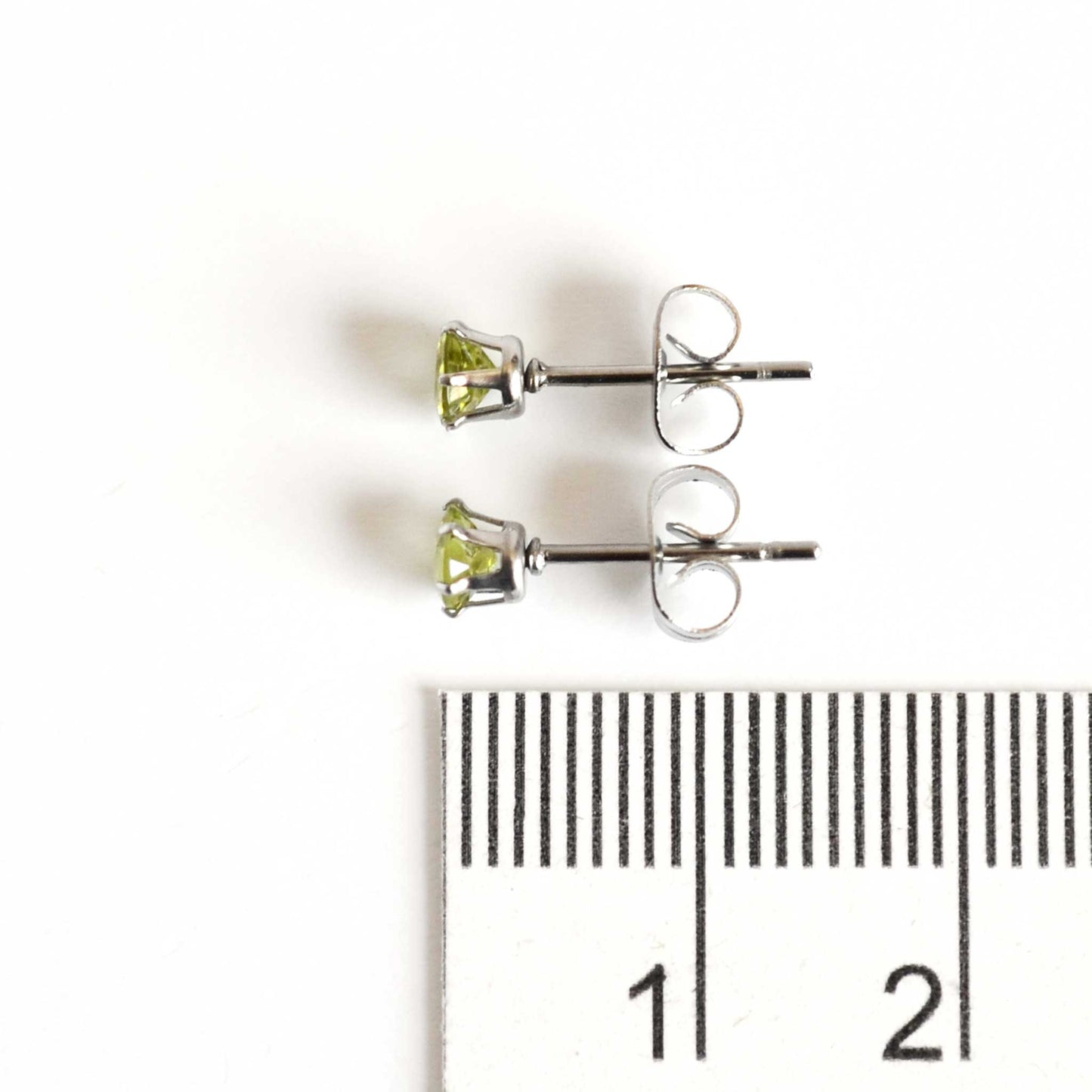 4mm Peridot gemstone stud earrings next to ruler