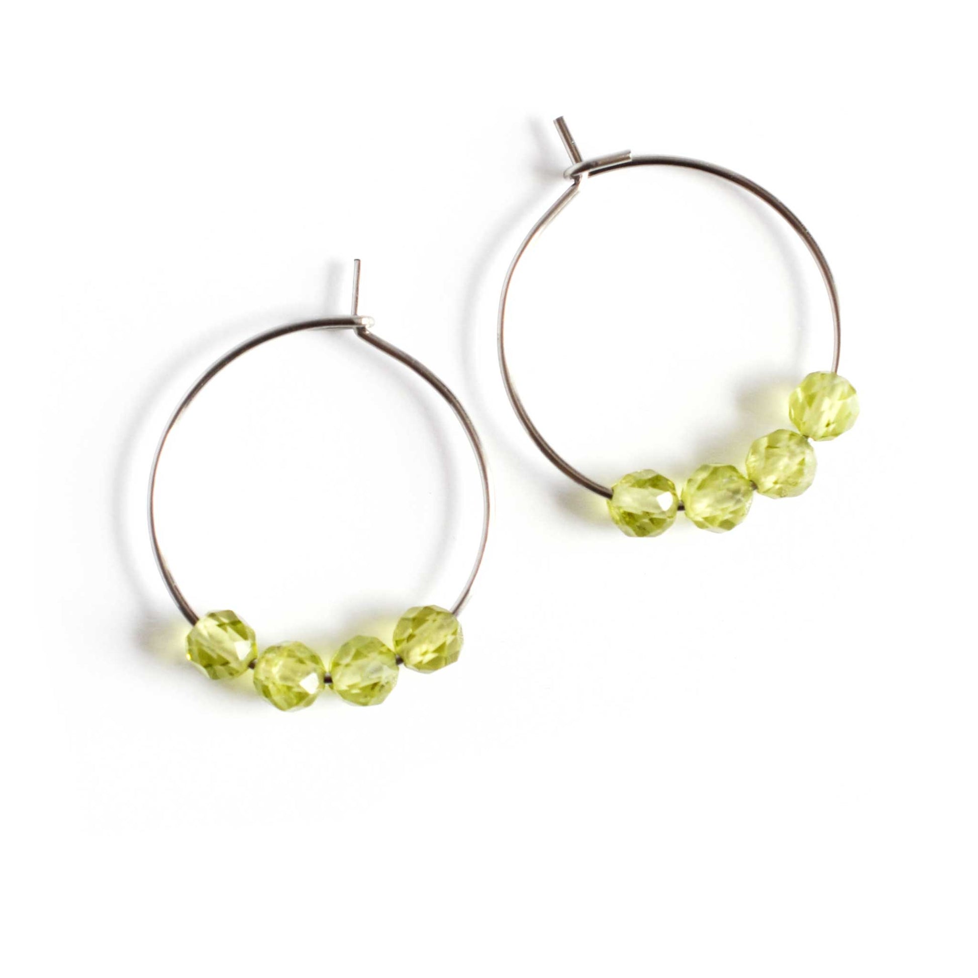 Pair of green Peridot gemstone hoop earrings on white background