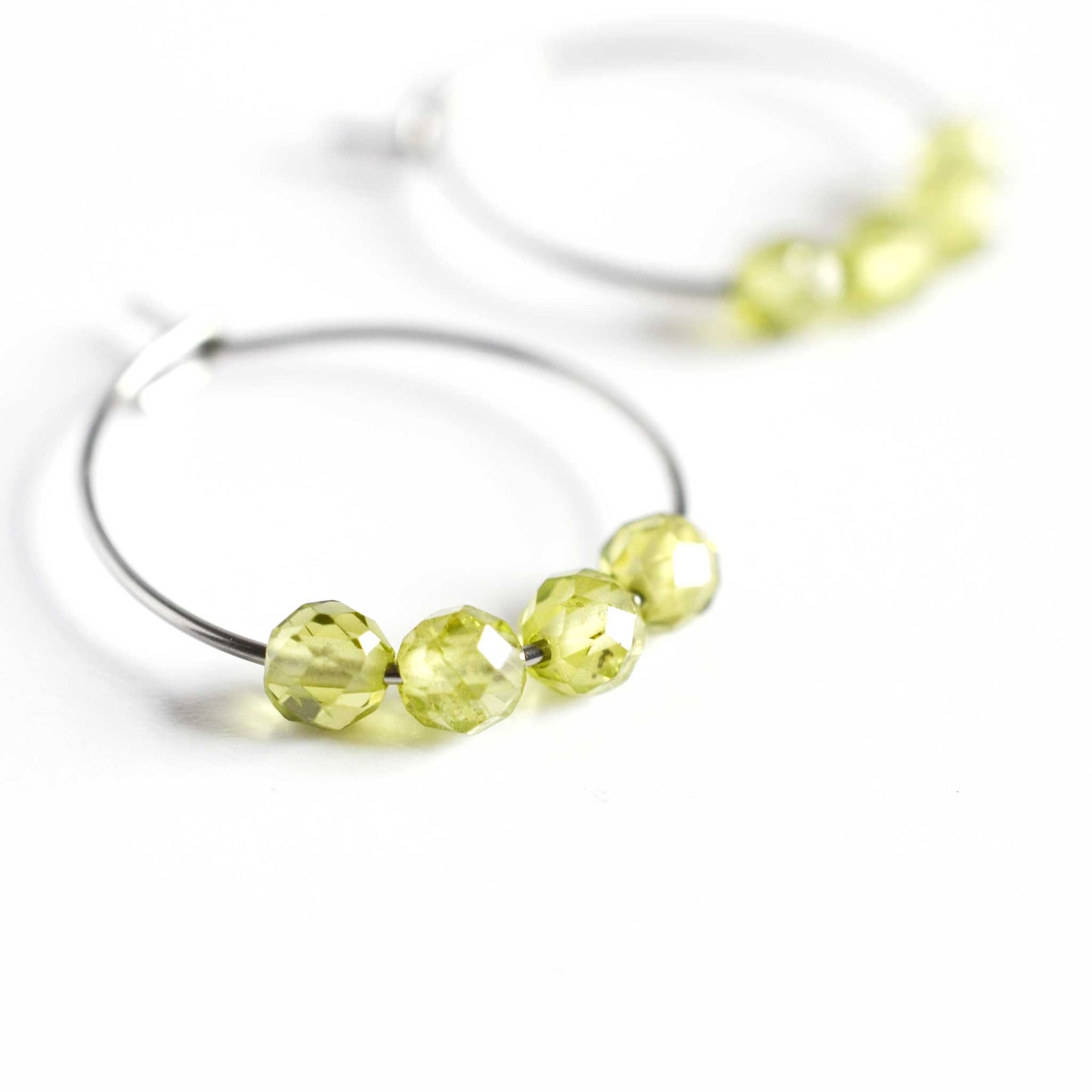 Close up of Peridot hoop earrings with four small round faceted Peridot gemstone beads