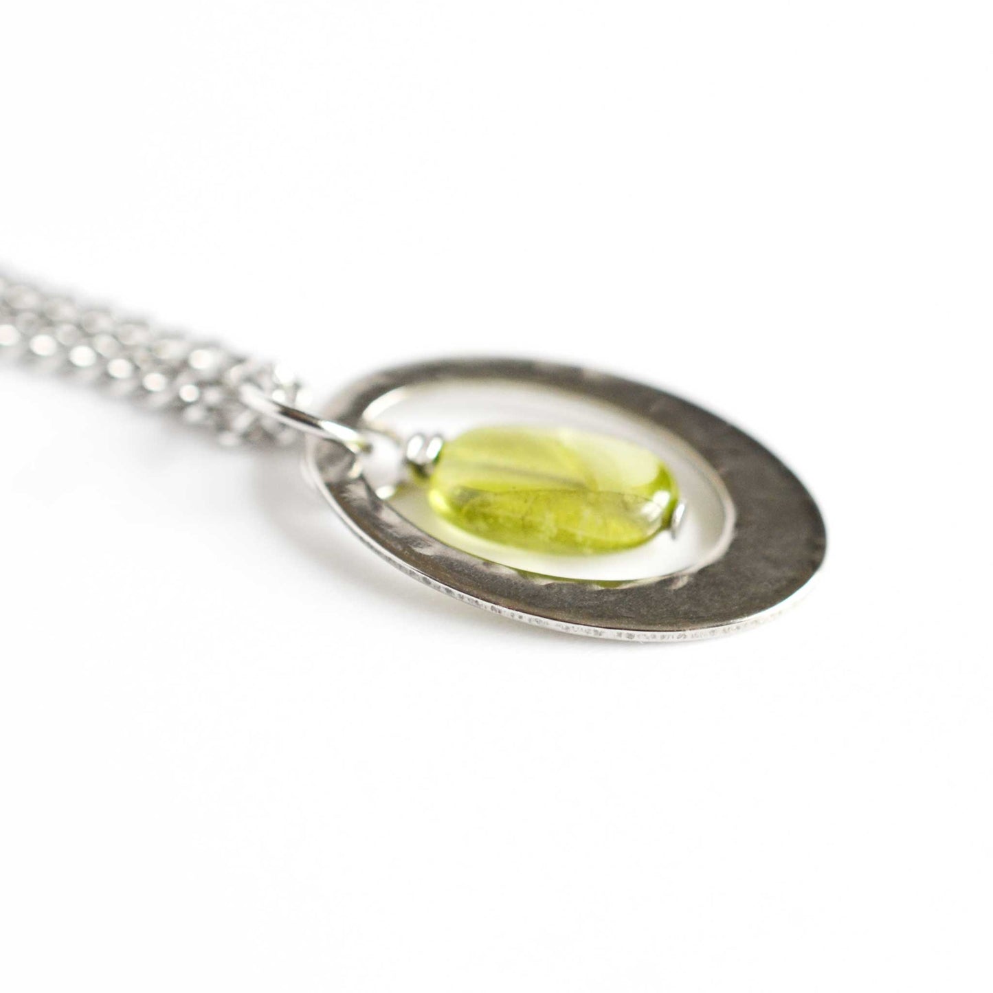 Close up view of green Peridot and silver stainless steel oval pendant necklace.