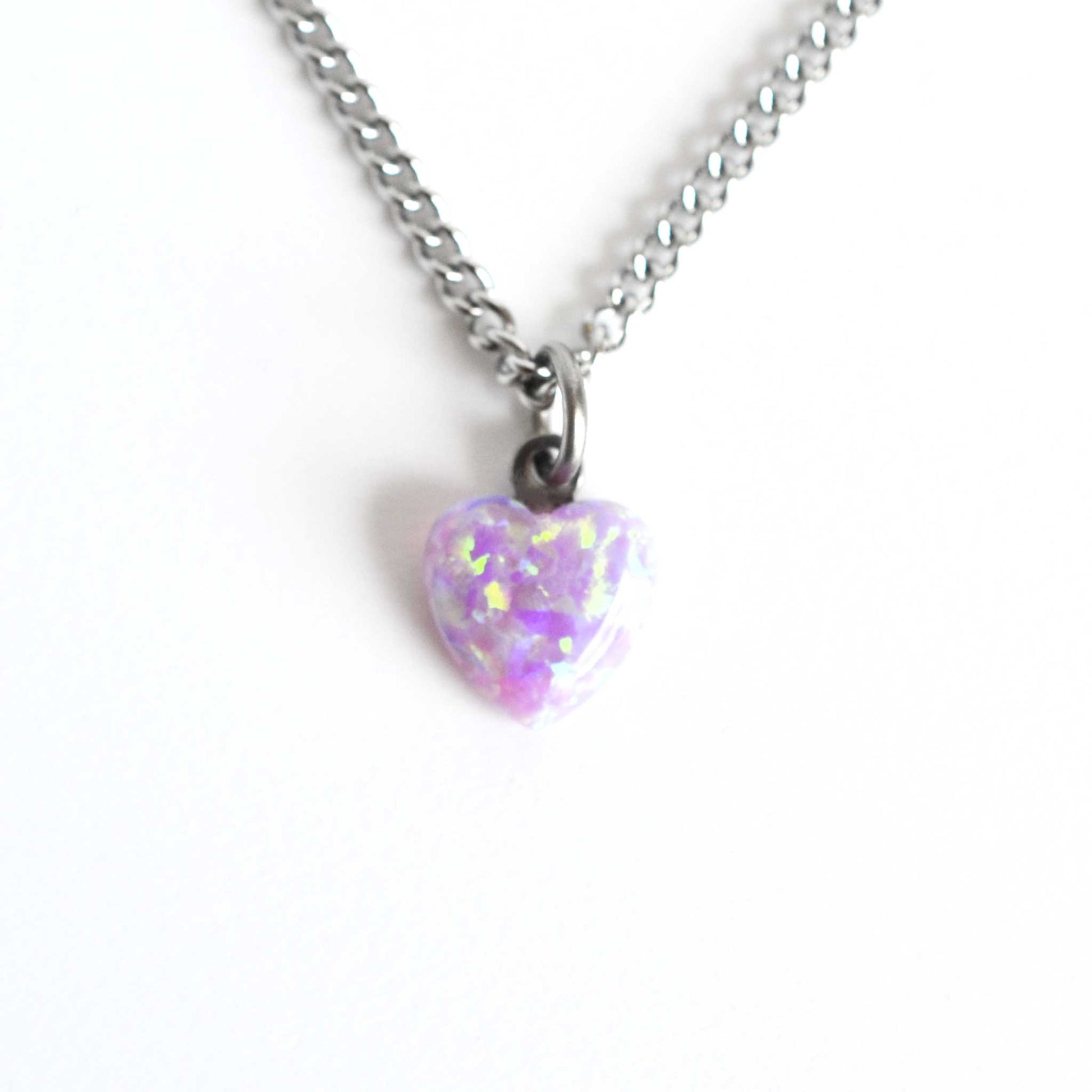 Dainty pink heart necklace with stainless steel chain on white background