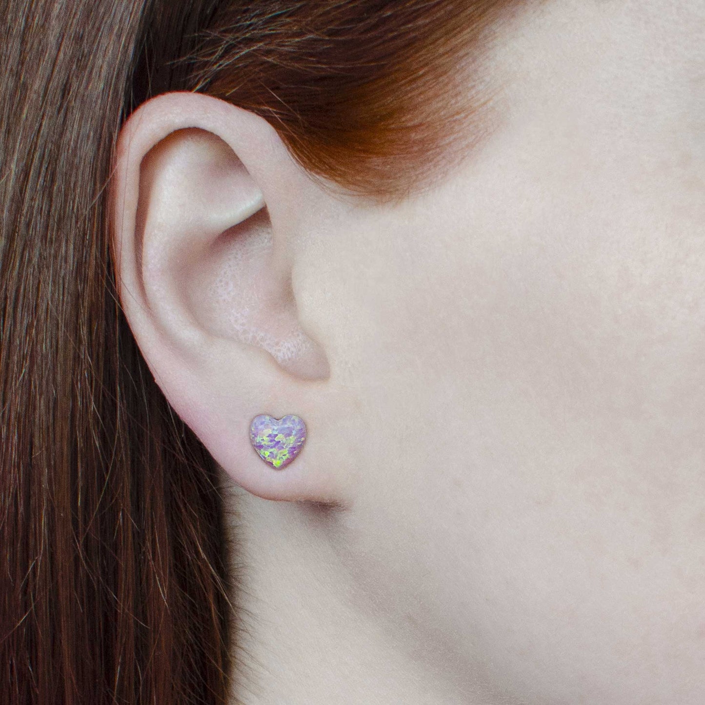 Woman wearing pink heart earrings in earlobe