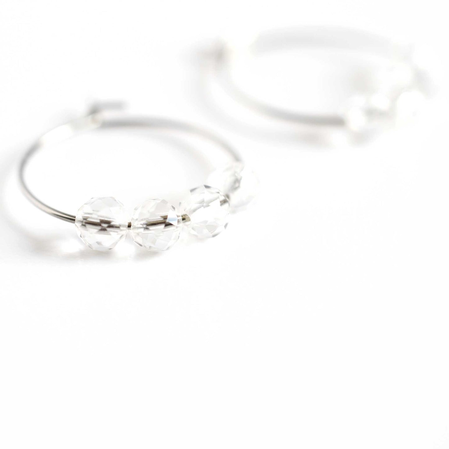 Close up of Rock Crystal hoop earrings with four small round faceted Clear Quartz gemstone beads