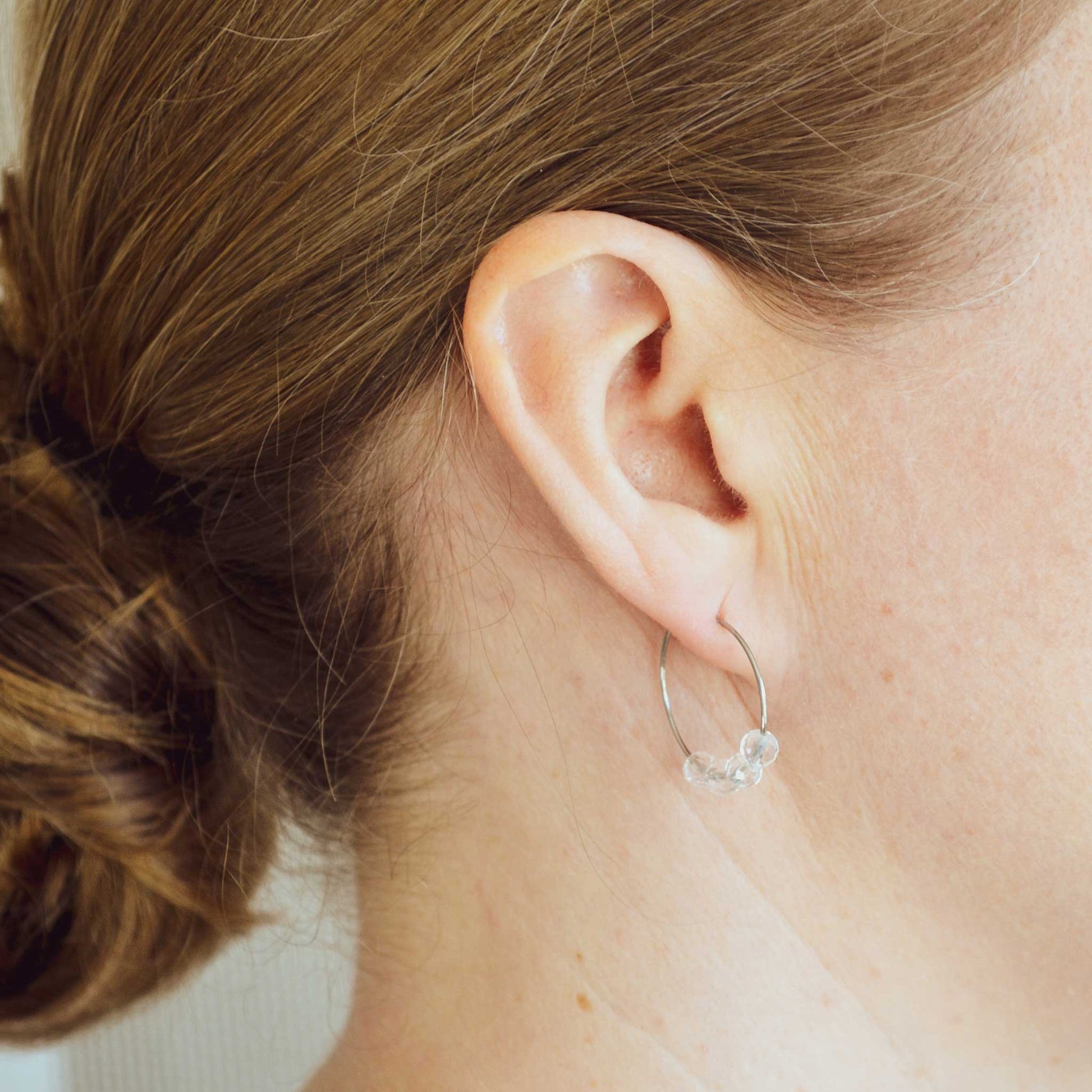 Woman wearing Clear Quartz earring hoop in earlobe