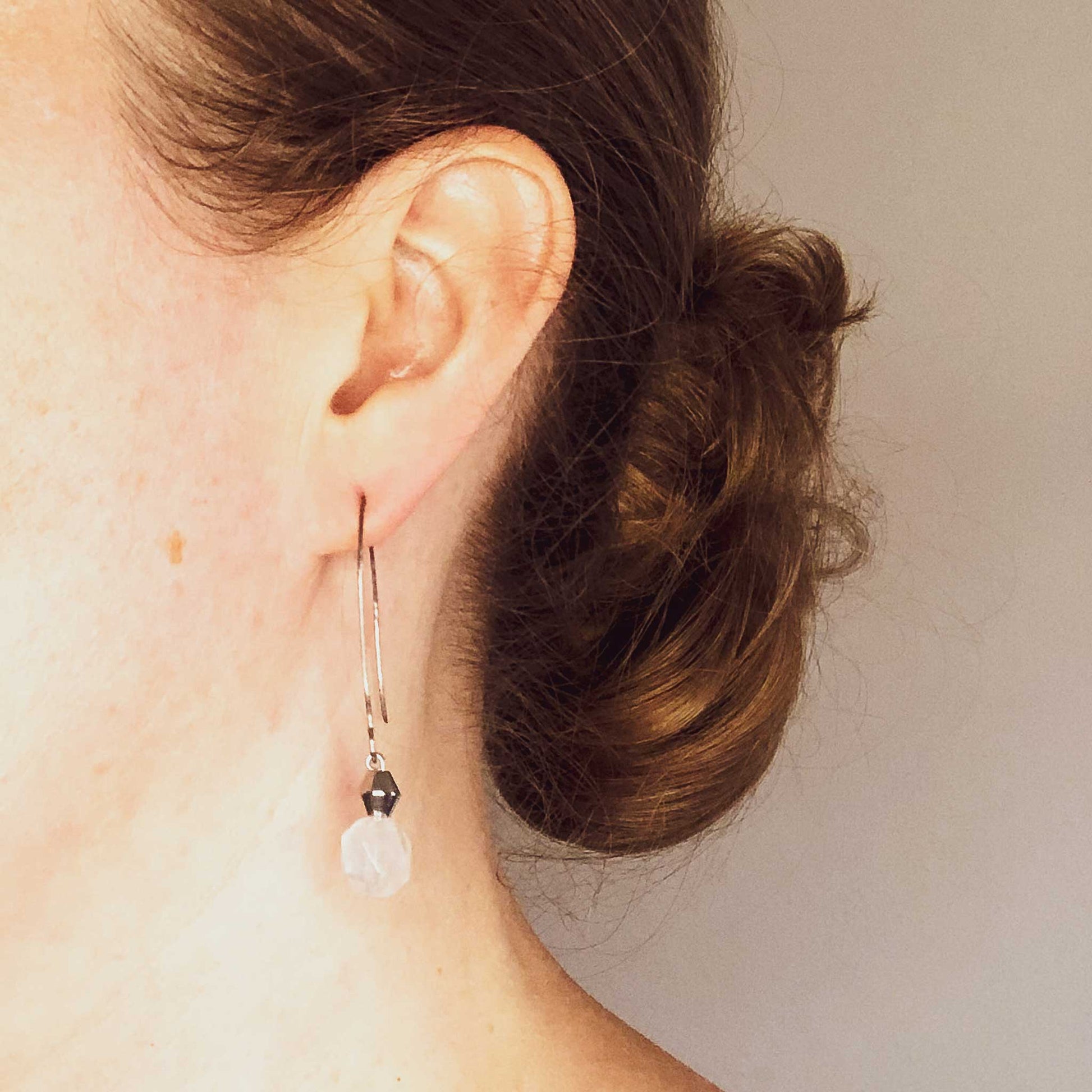 Woman wearing long Rose Quartz drop earrings.