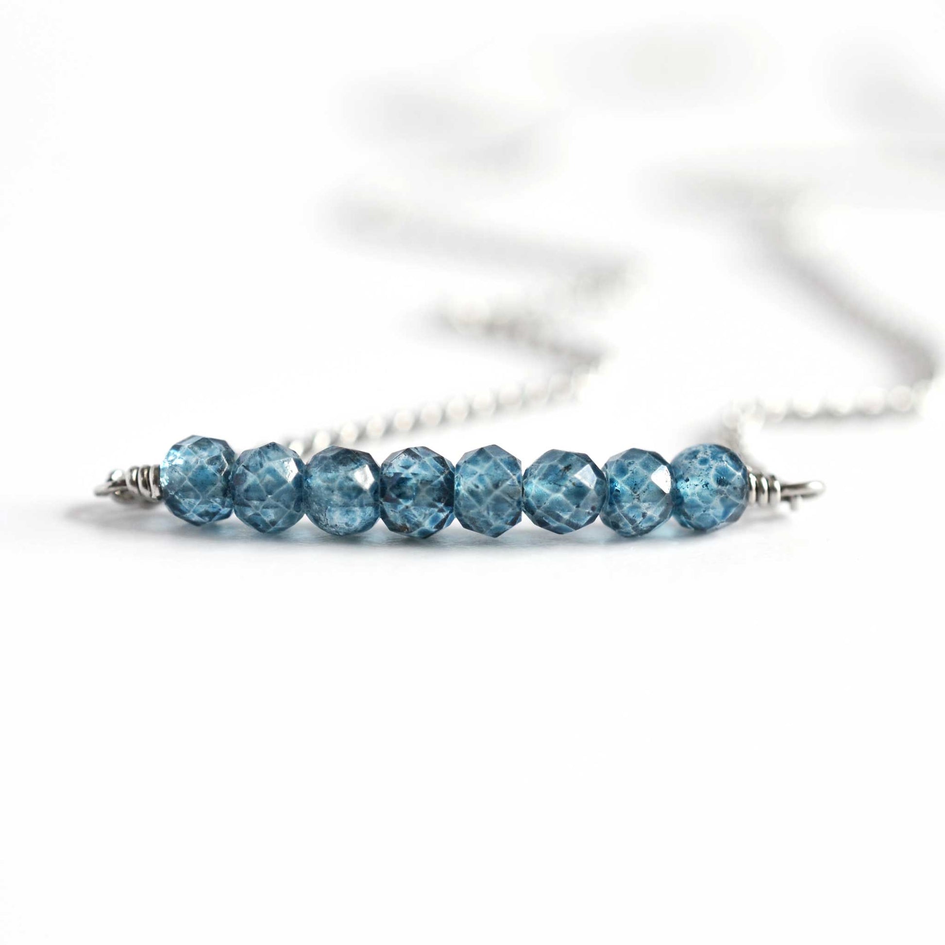 Close up of blue Topaz necklace with seven small round faceted blue Topaz gemstone beads