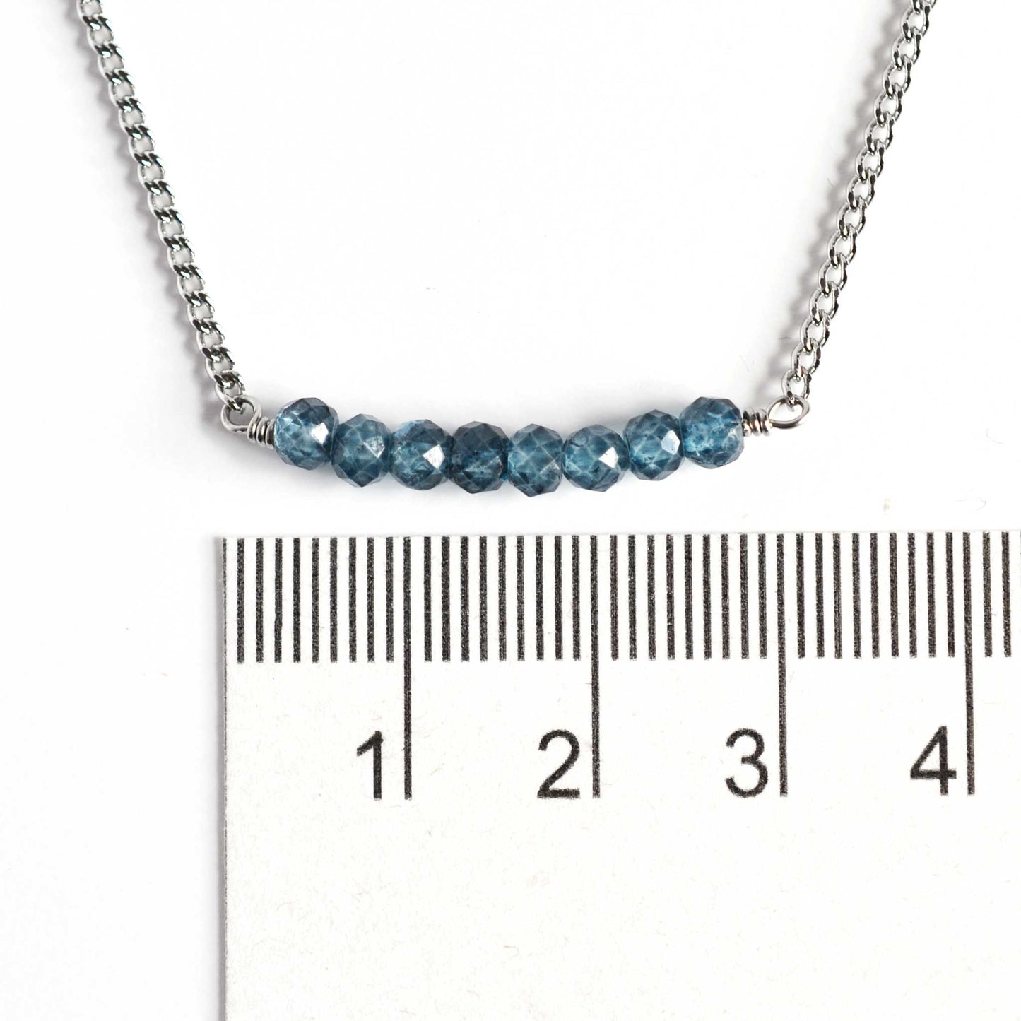 Dainty blue Topaz necklace with 4mm gemstone beads next to ruler