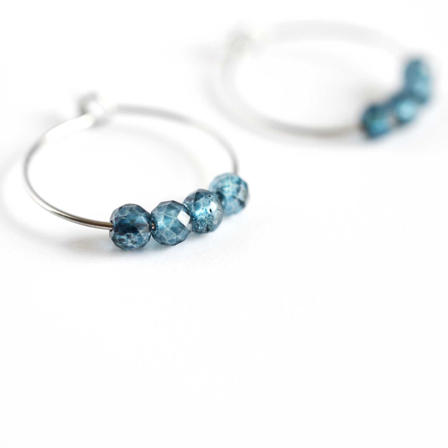 Close up of Topaz hoop earrings with four small round faceted blue Topaz gemstone beads