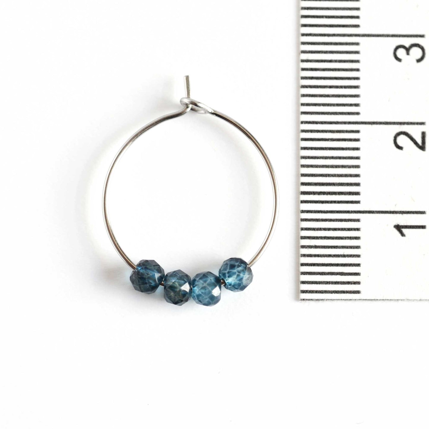 2cm diameter blue Topaz hoop earring next to ruler