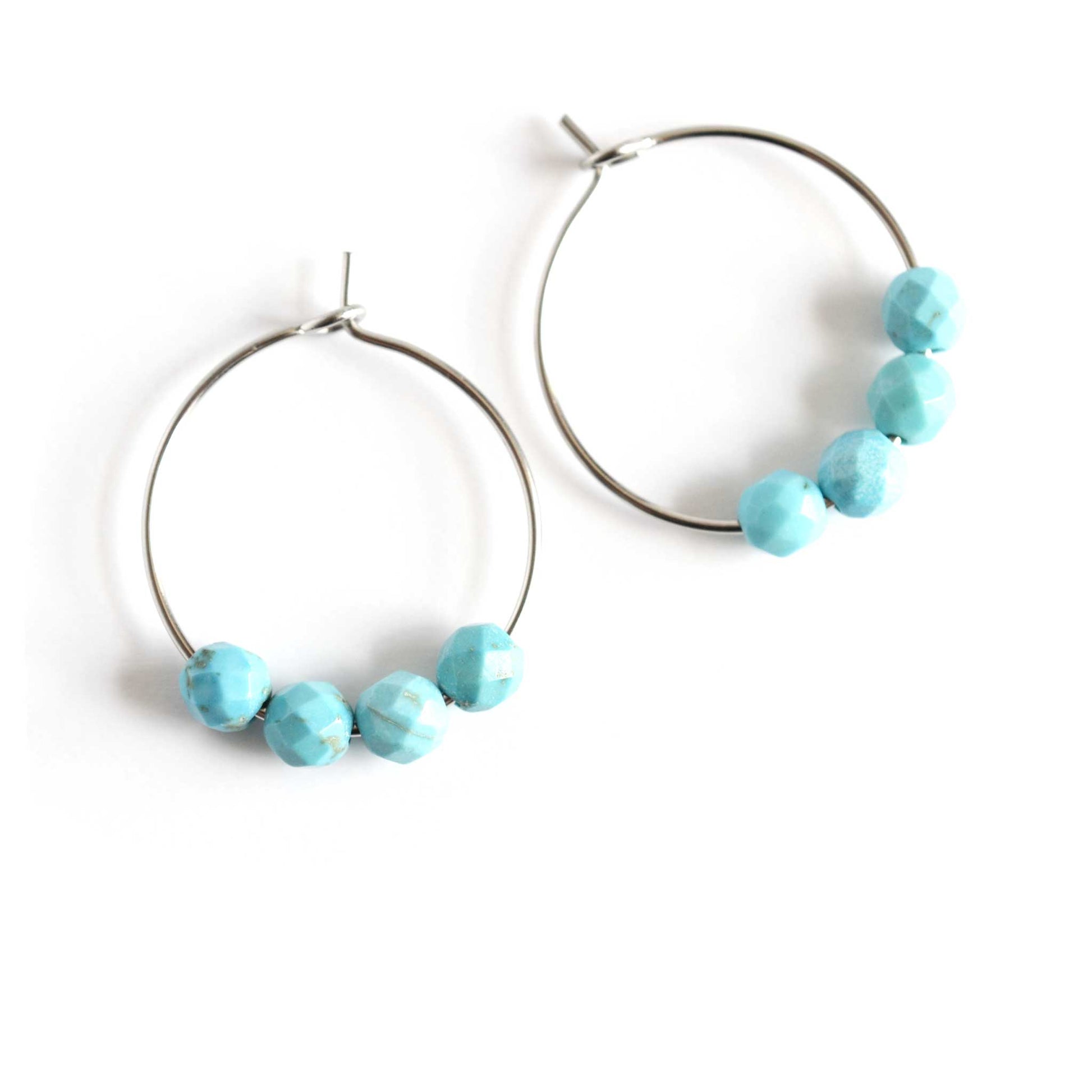 Pair of surgical steel hoop earrings with Turquoise gemstones on white background